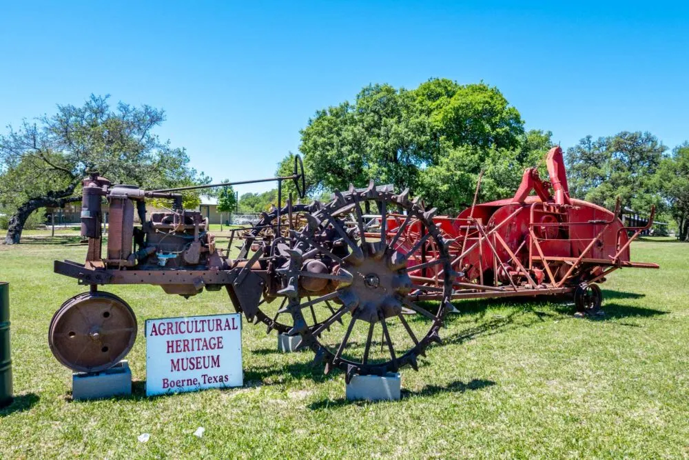 Antique metal tractors and farm equipment with a sign for the Agricultural Heritage Museum, Boerne, Texas