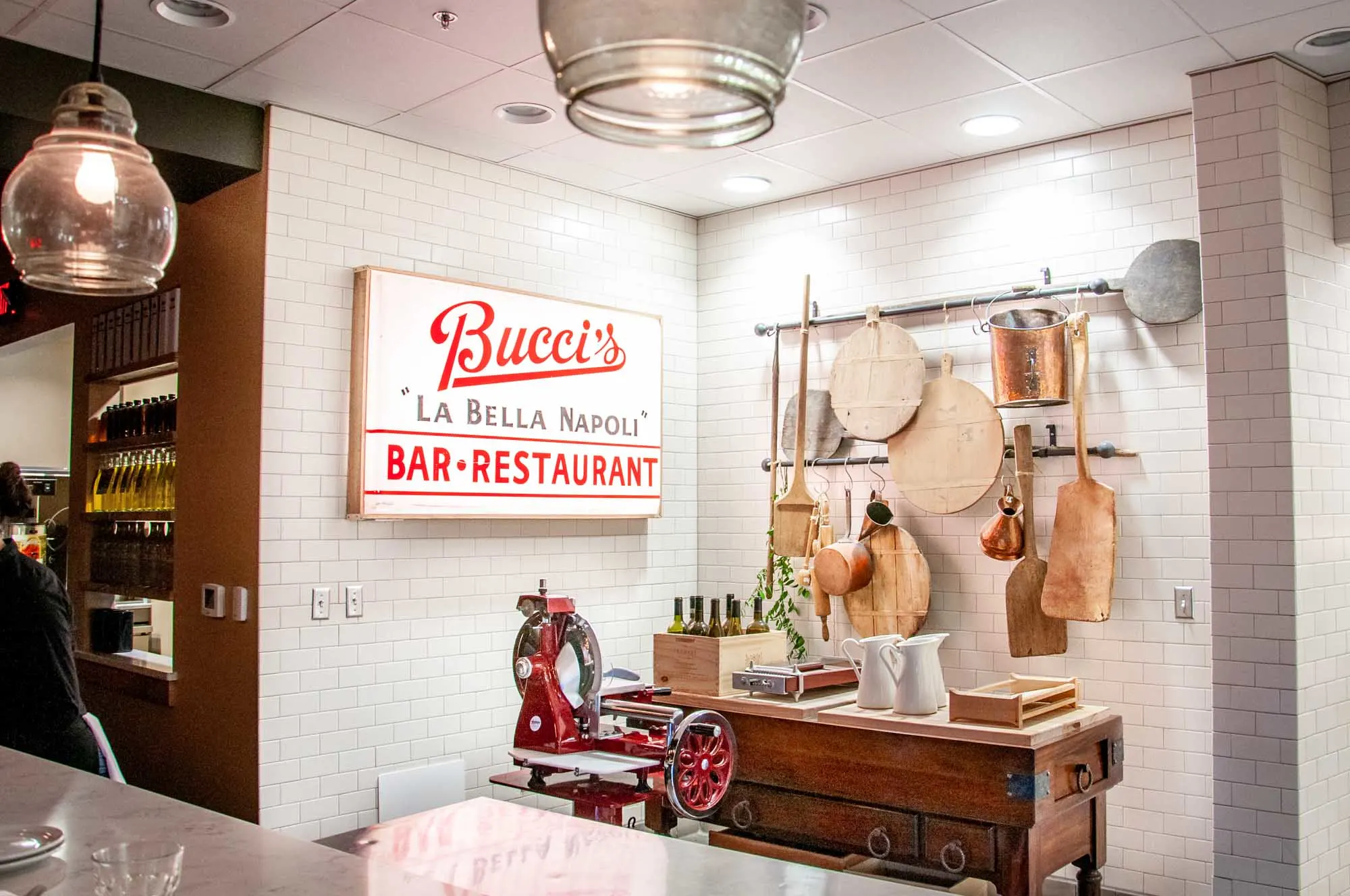 Cutting boards and other tools hanging on a restaurant wall beside a sign for Bucci's Bar & Restaurant