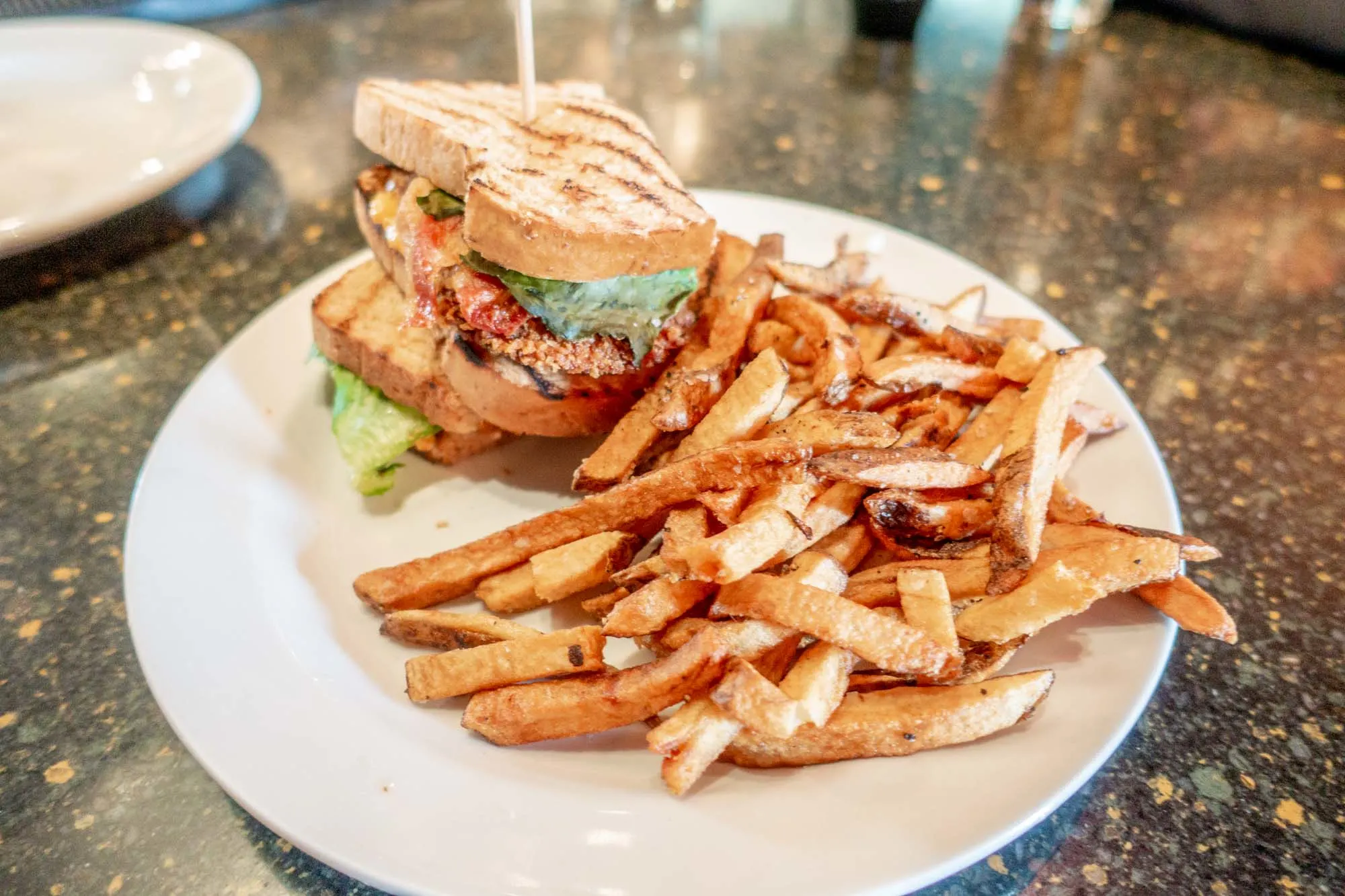 Fried green tomato BLT sandwich on a plate with French fries
