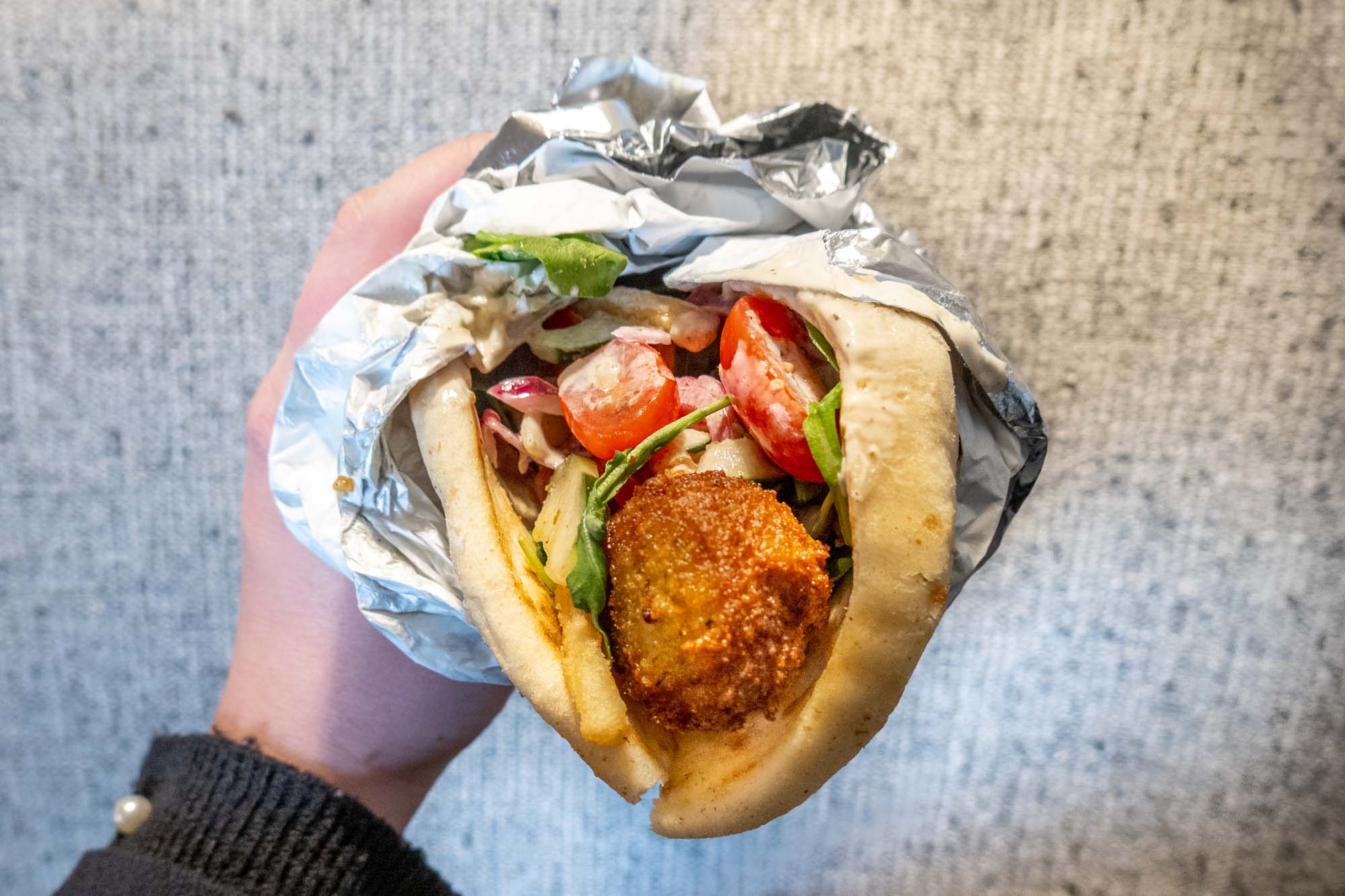 Falafel in a pita with tomatoes, lettuce, and sauce