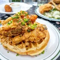 Fried chicken and waffles on a plate on a table with other dishes