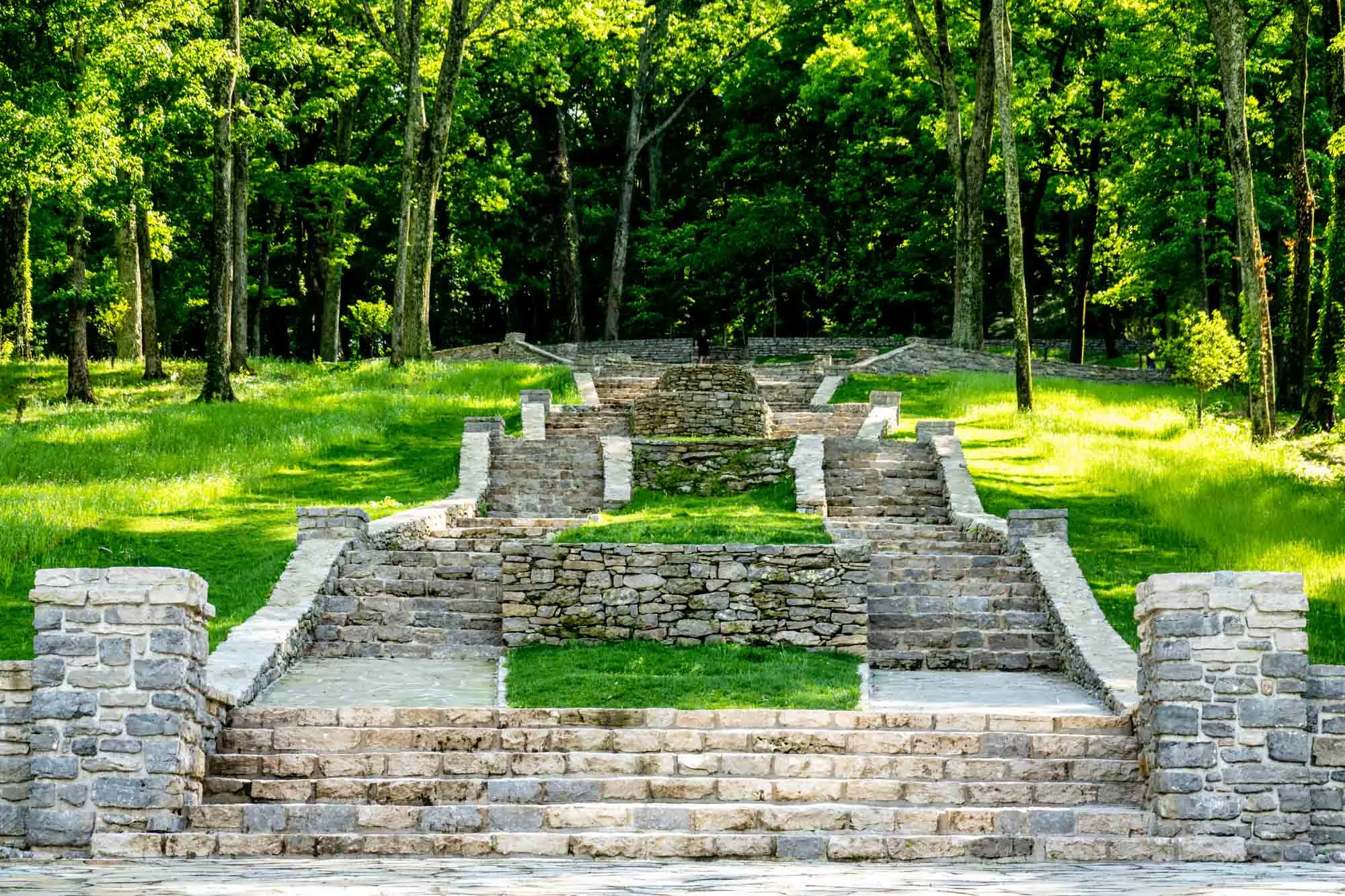 Multiple staircases in a park filled with grass and trees.