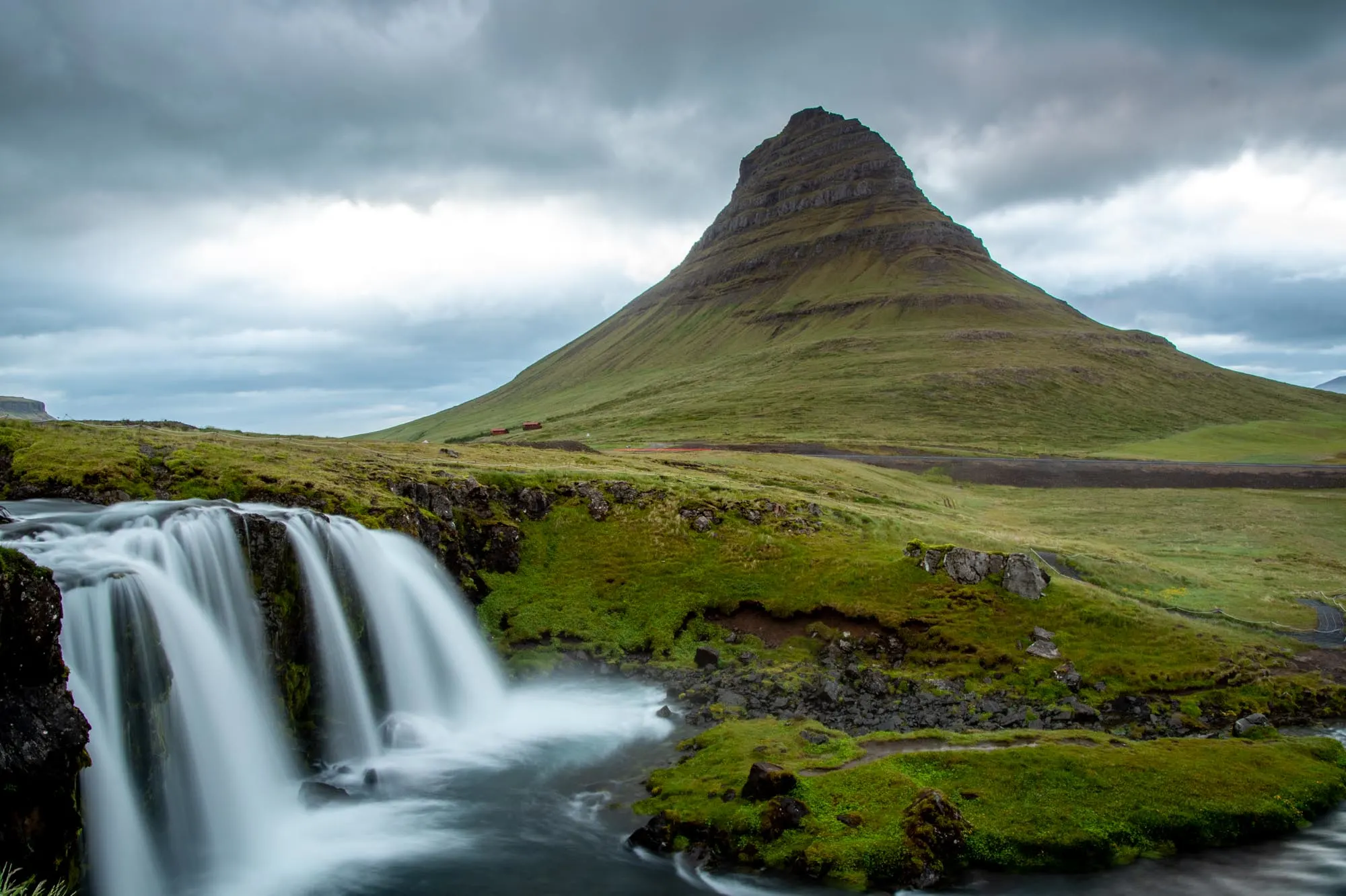 Grass-covered mountain with a waterfall in the foreground