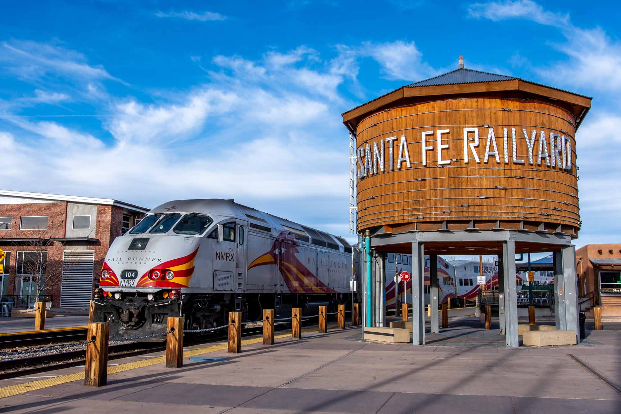 Round water tower labeled "Santa Fe Railyard" next to a gray train.