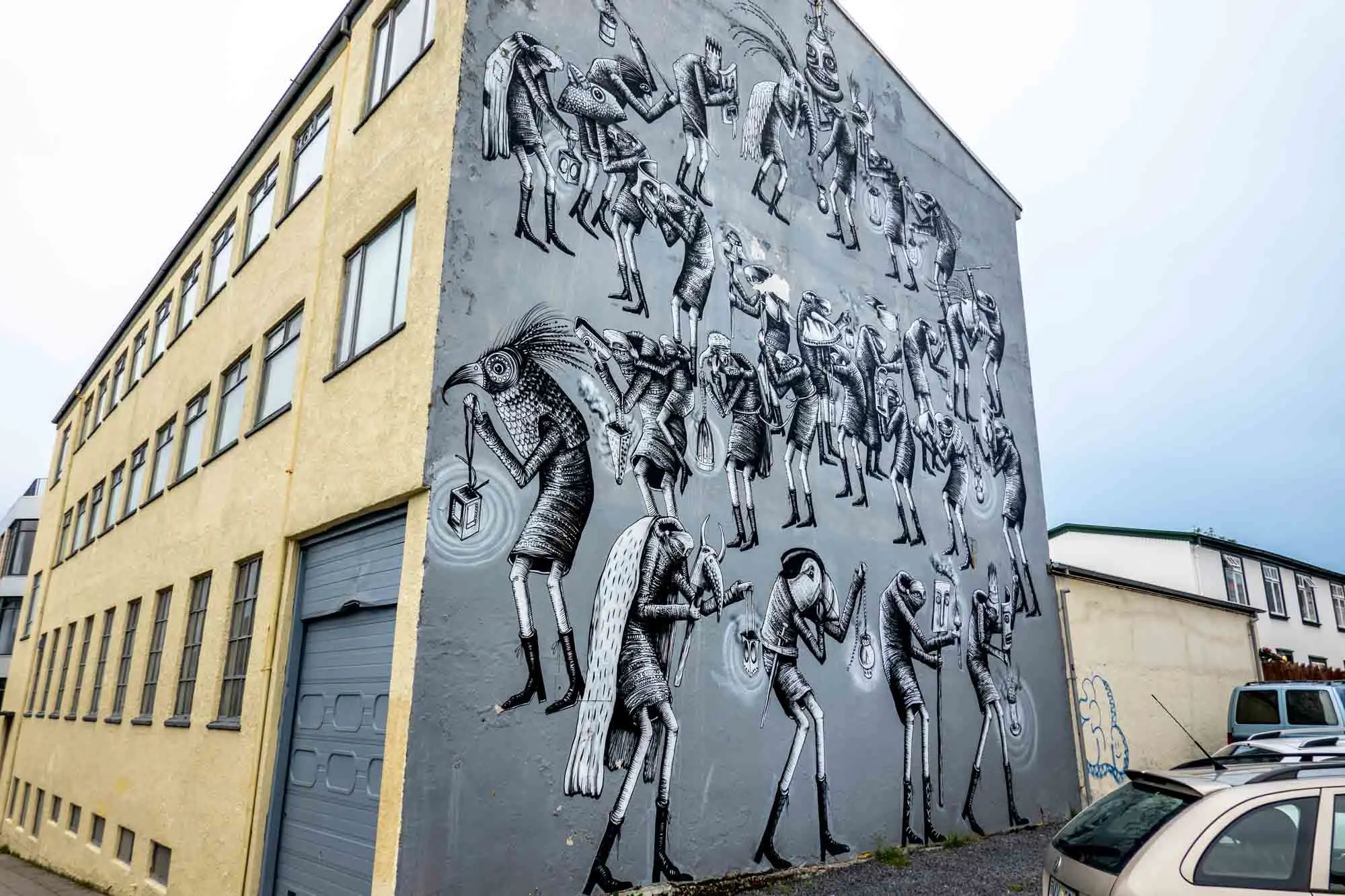 Mural on side of building with people in bird-head costumes