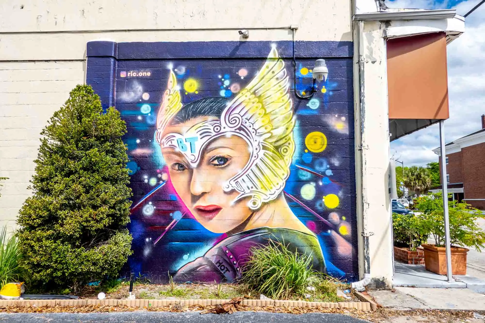 Street art mural of a woman wearing a purple costume and a headpiece with gold wings