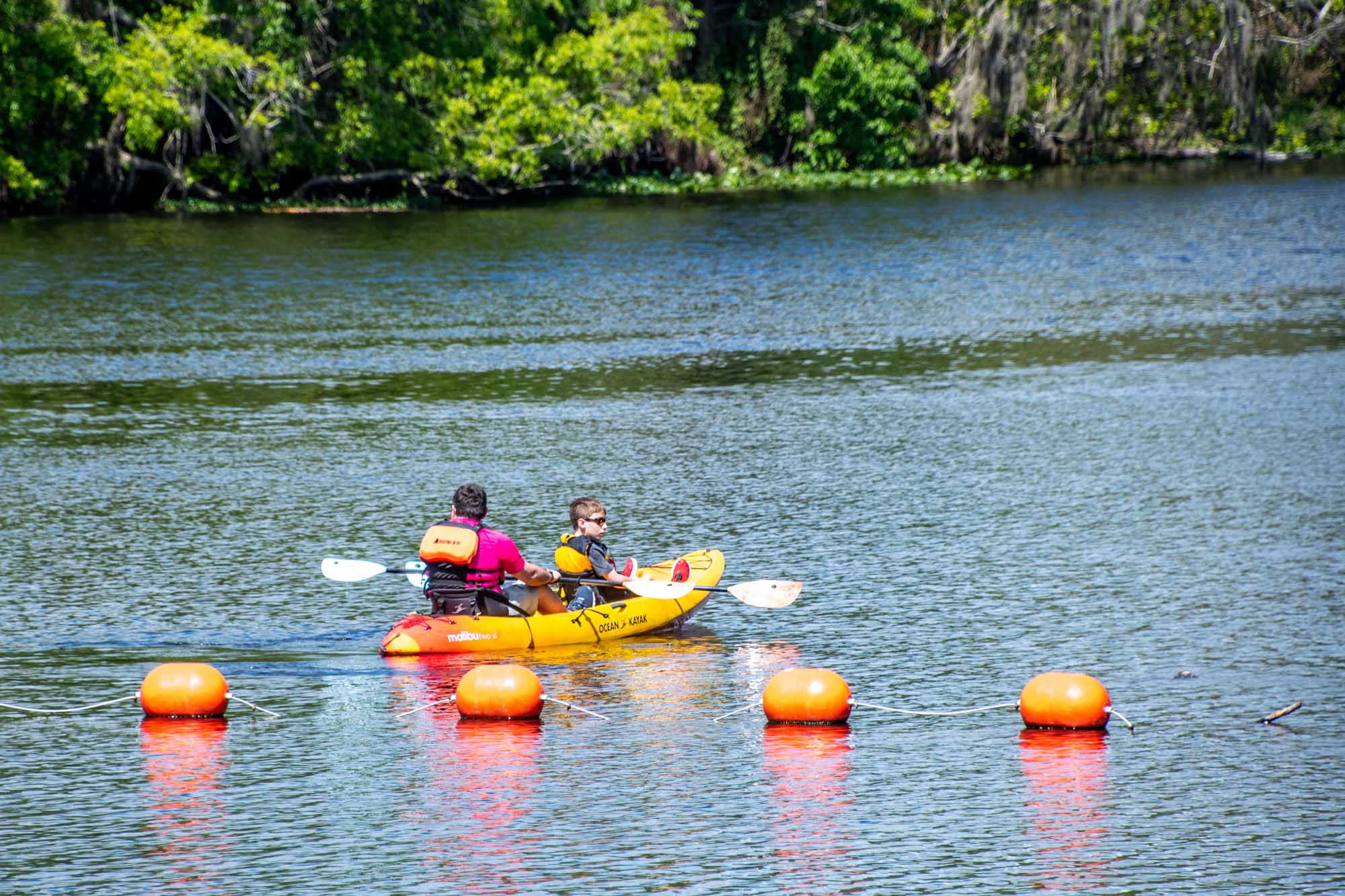 Two people in yellow kayak near orange bouys