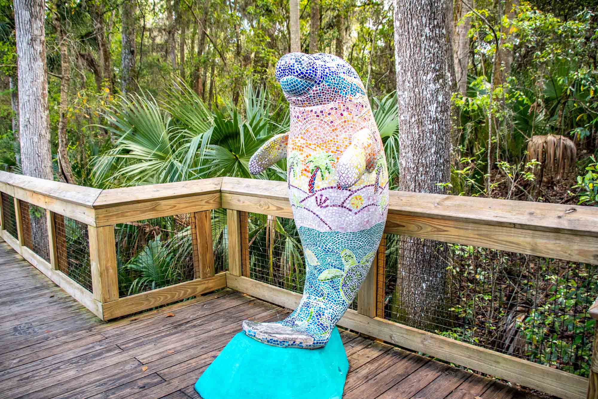 Colorful mosaic manatee statue on wooden boardwalk