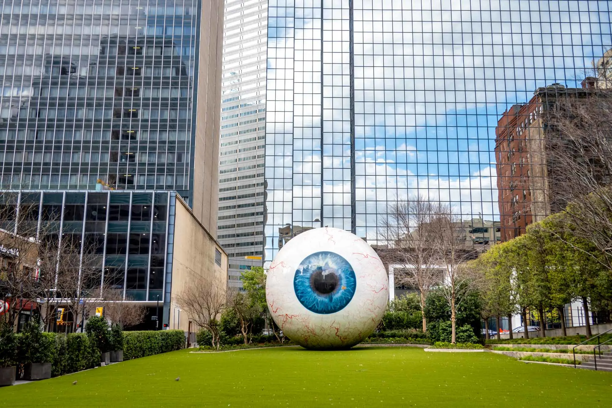 Giant eyeball sculpture on grass in front of office buildings