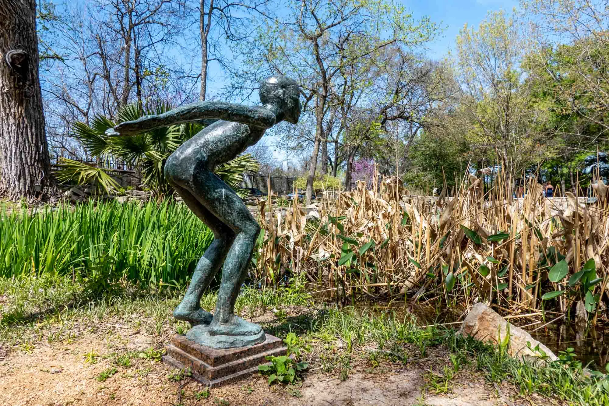 Bronze sculpture of a child jumping into a pond filled with reeds