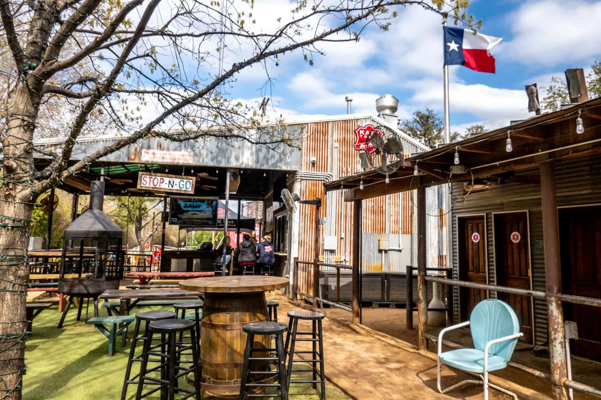 Outdoor seating at a beer garden and a Texas flag blowing in the wind.