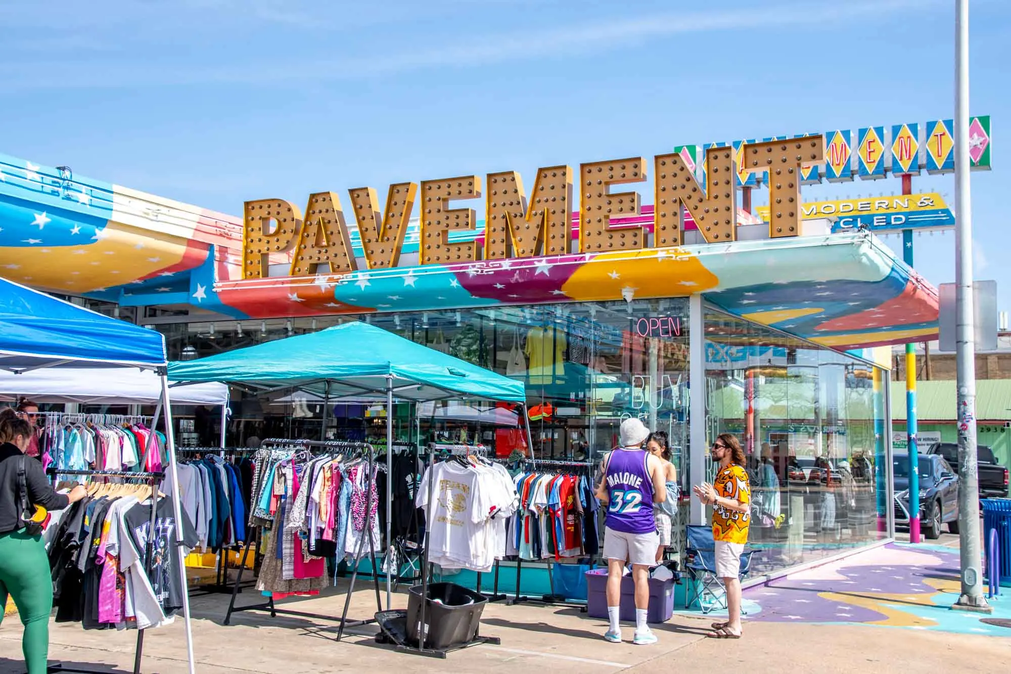 People shopping at racks of clothes set up outside Pavement thrift store