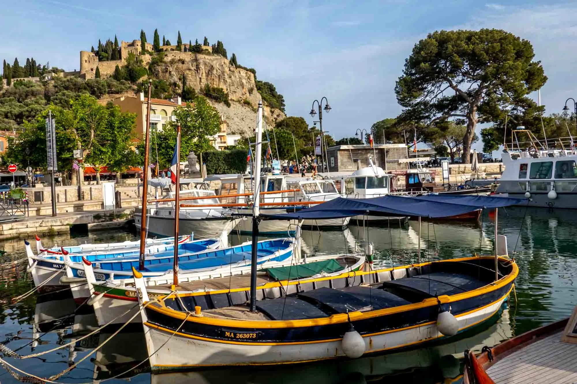 Colorful fishing boats in a marina with a hilltop building in the background