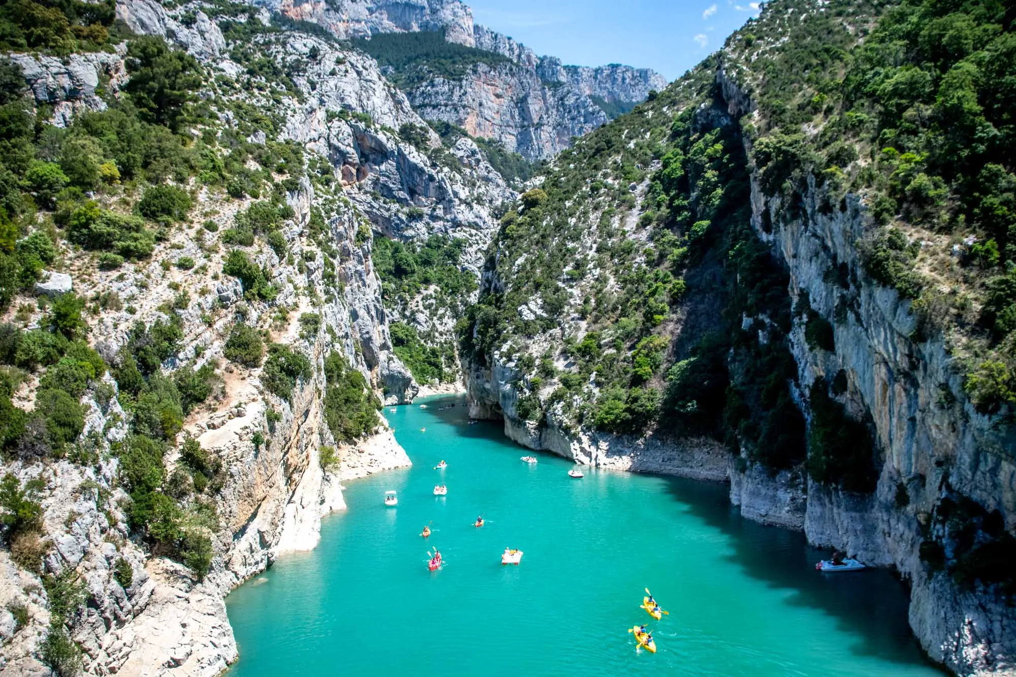 Overhead view of people kayaking in a river gorge surrounded by limestone cliffs