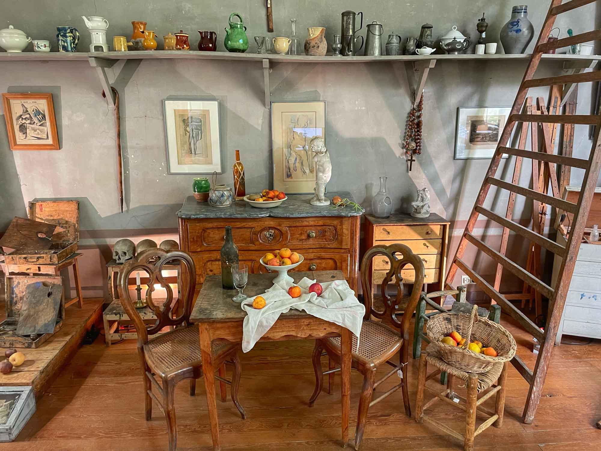Artist's studio with table and chairs, dresser, and fruit