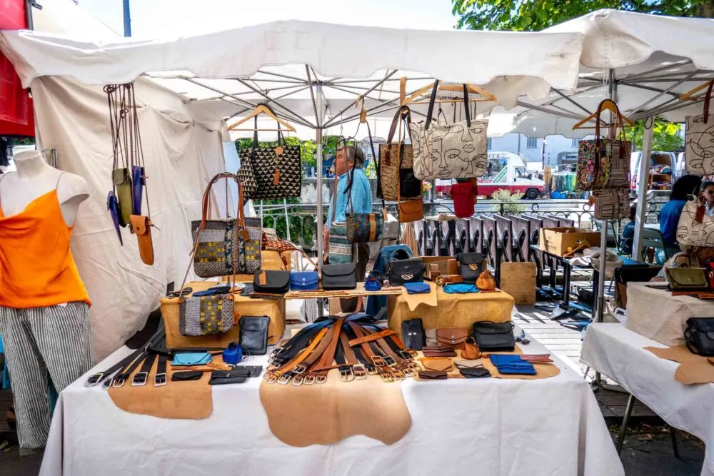 Leather goods including bags and belts displayed for sale at an outdoor market 