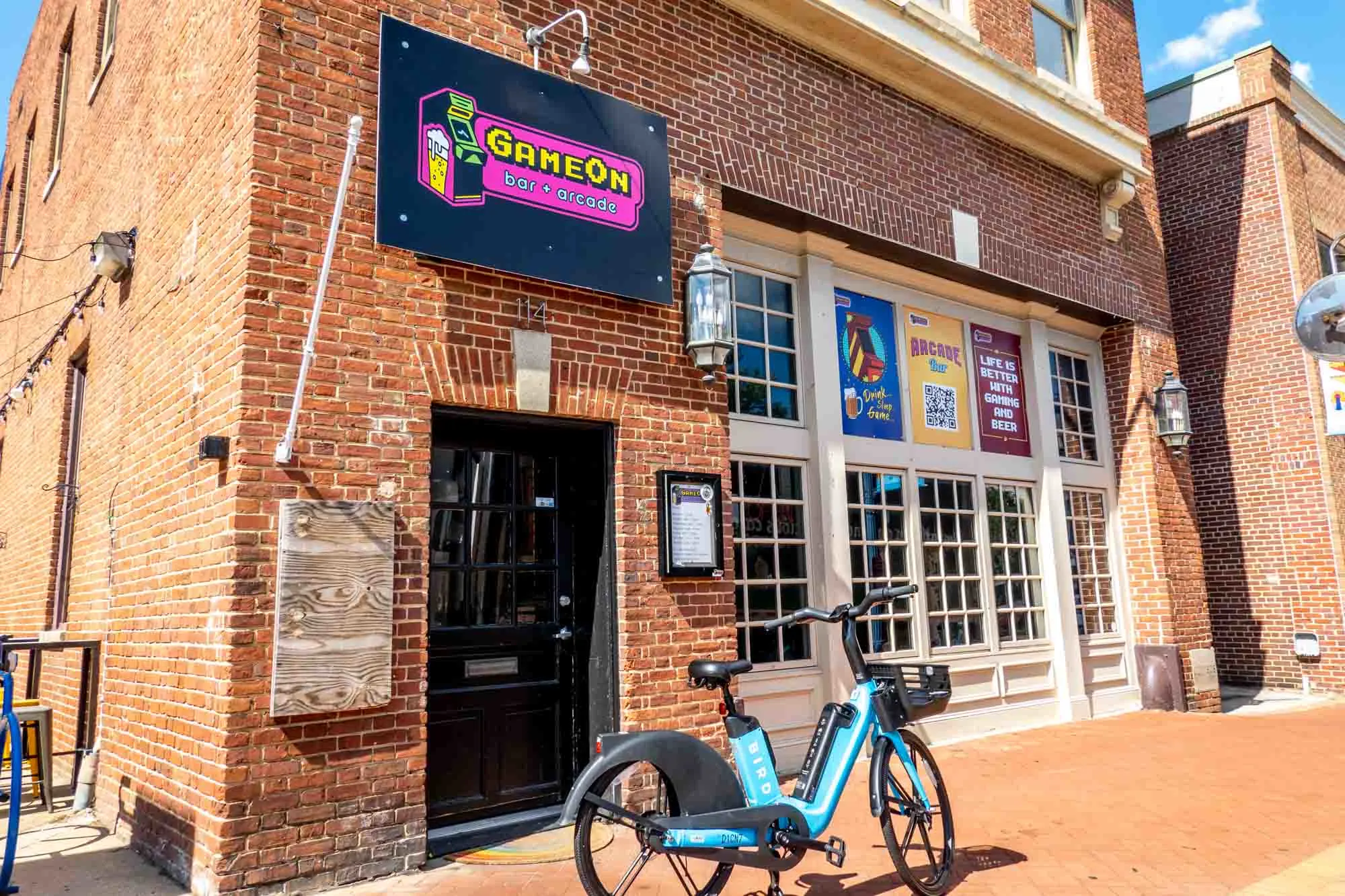 Red brick building with a black and pink sign: "GameOn, bar + arcade."