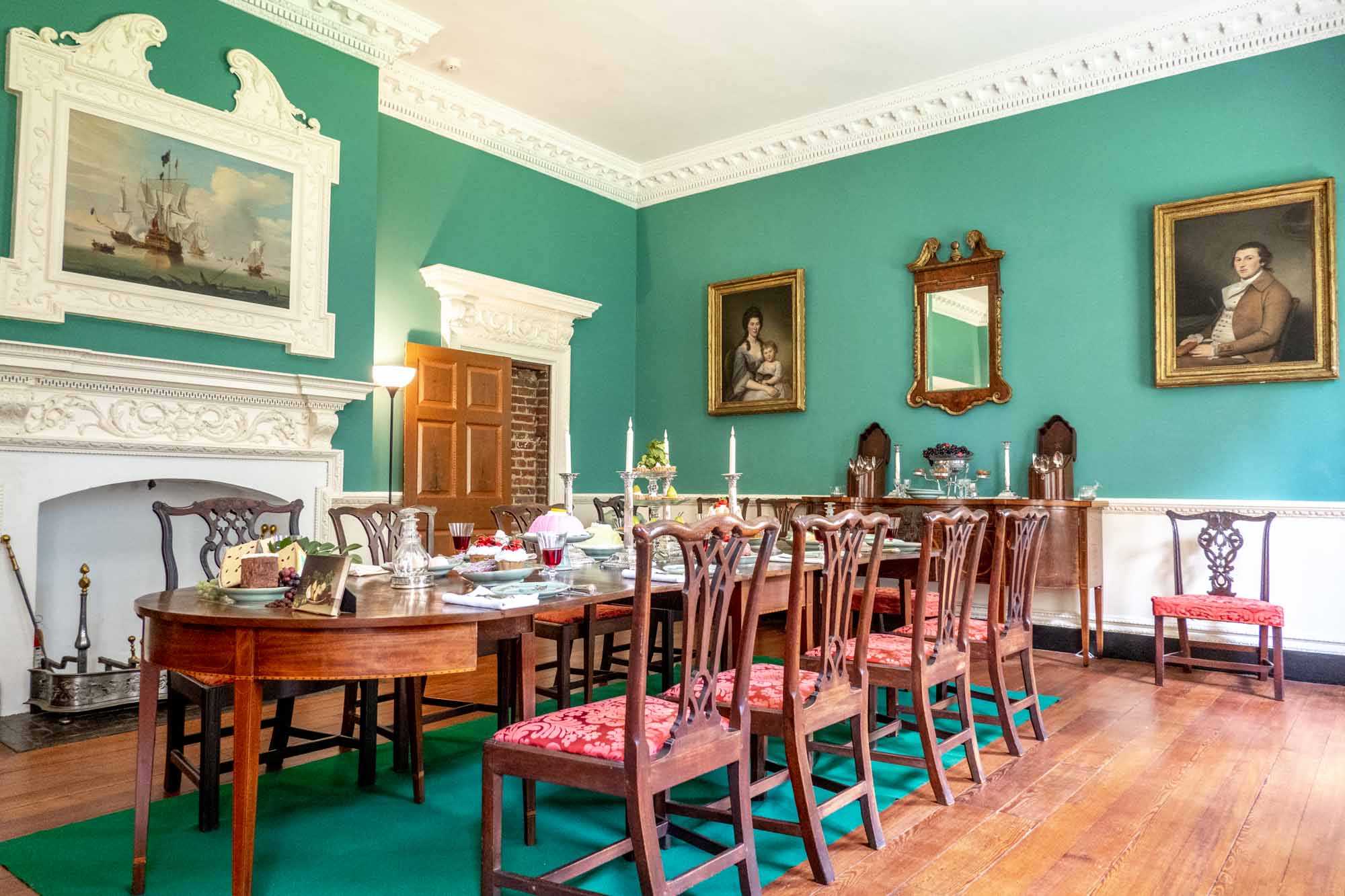 Dining room with portraits on its turquoise walls and formal dining table set for dinner