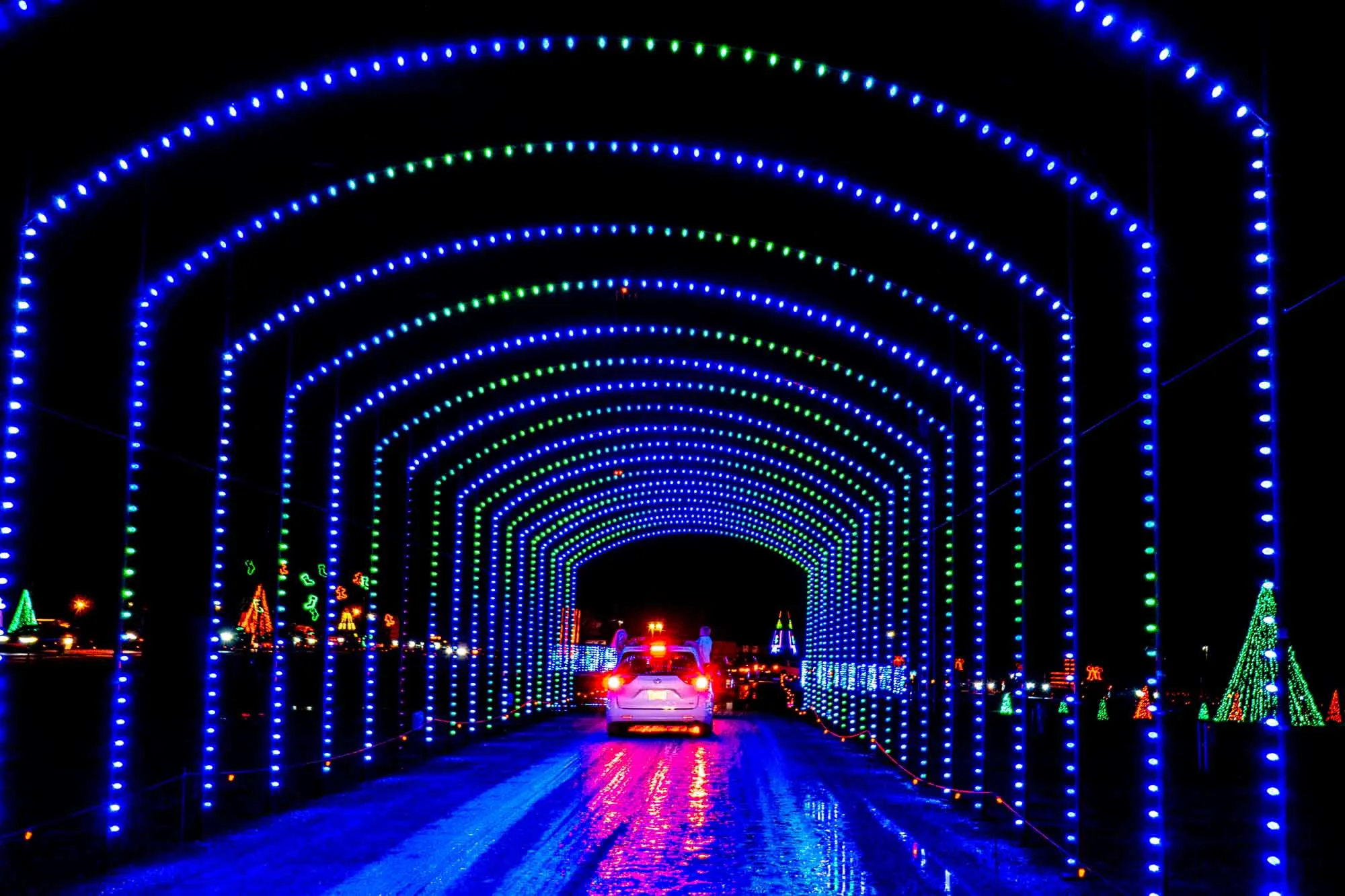 Car driving through a tunnel of Christmas lights
