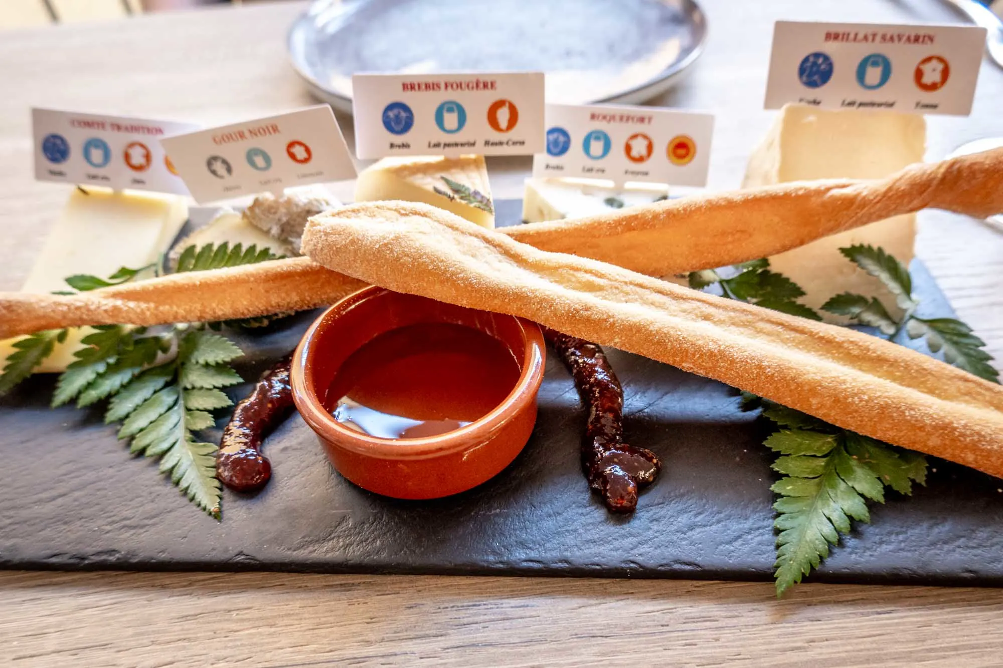 Slate platter with cheeses, jam, and breadsticks