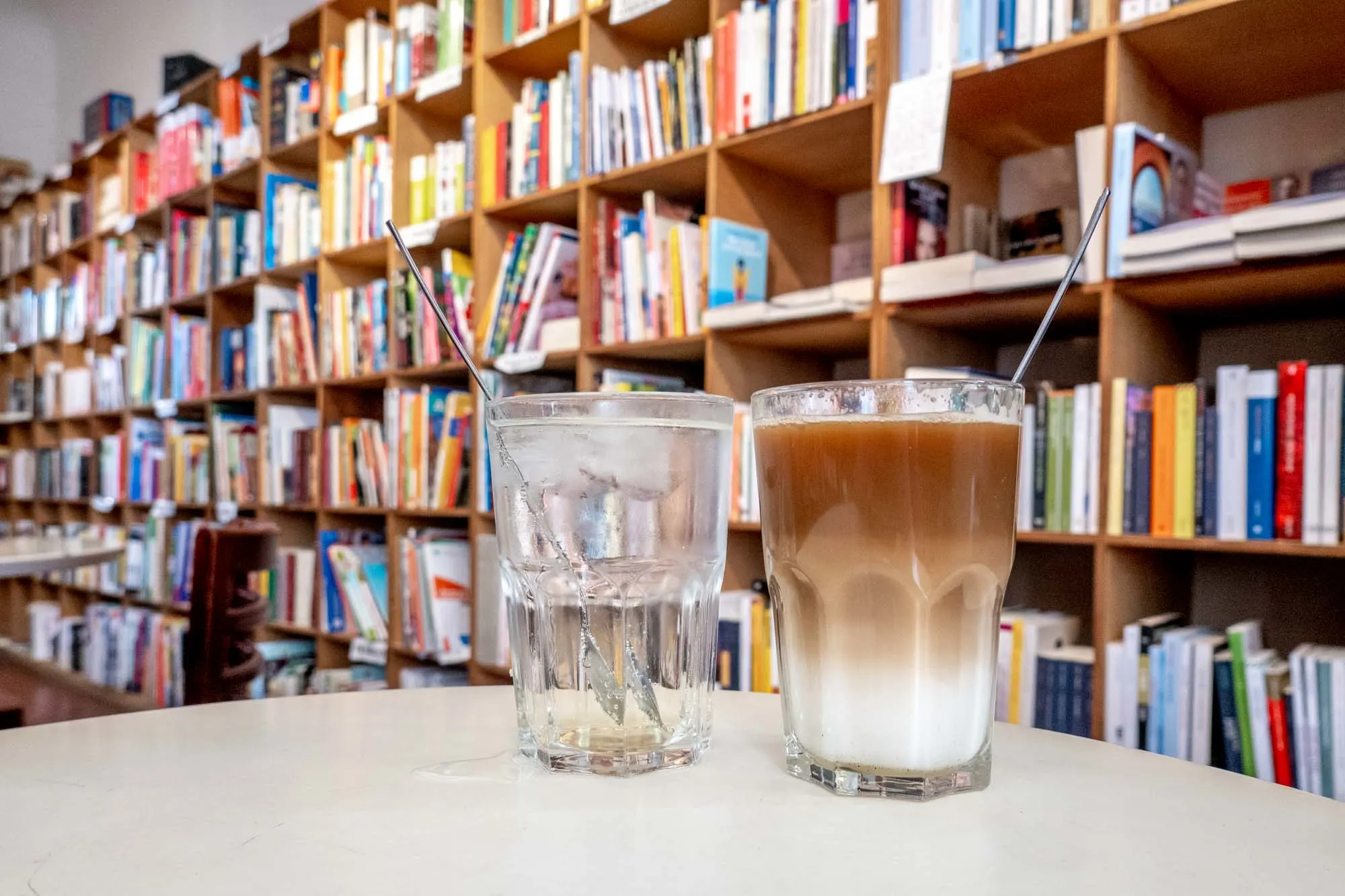 Two drinks on a table in front of a wall of books