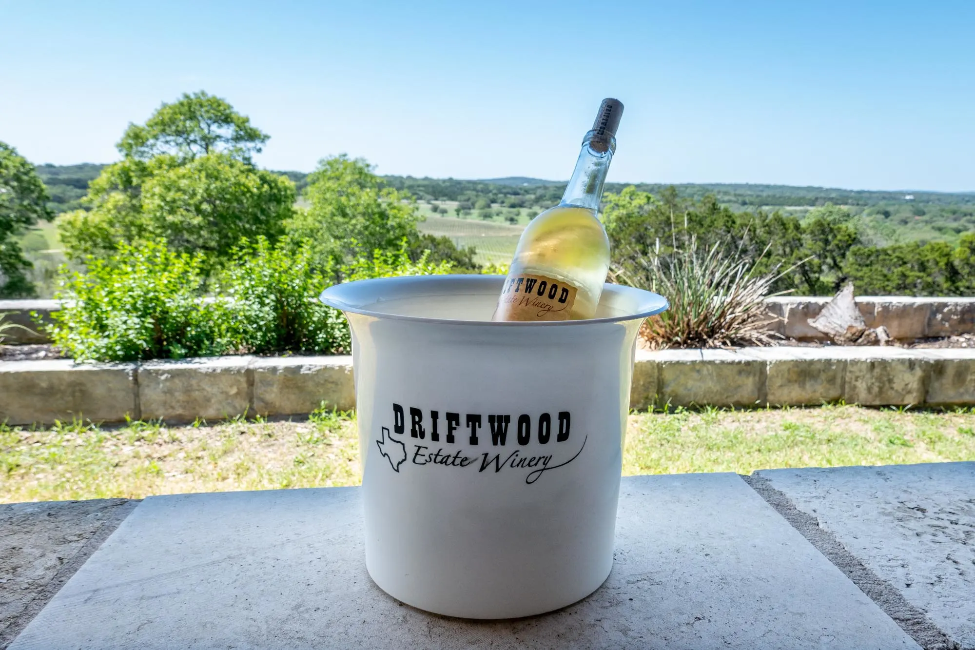 Bottle of white wine in a white ice bucket labeled "Driftwood Estate Winery"