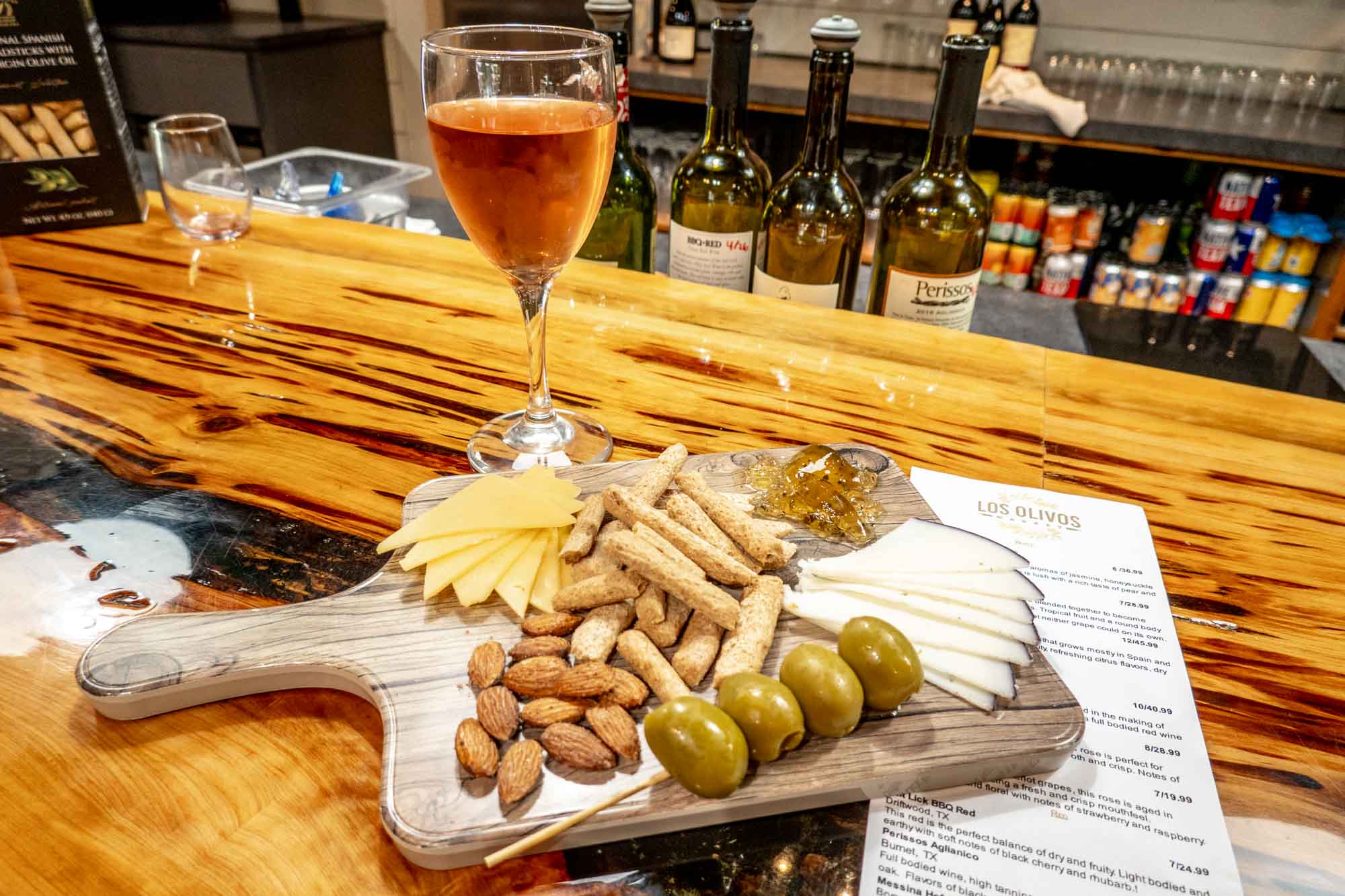 Cheese platter on a wooden board beside a glass of wine.