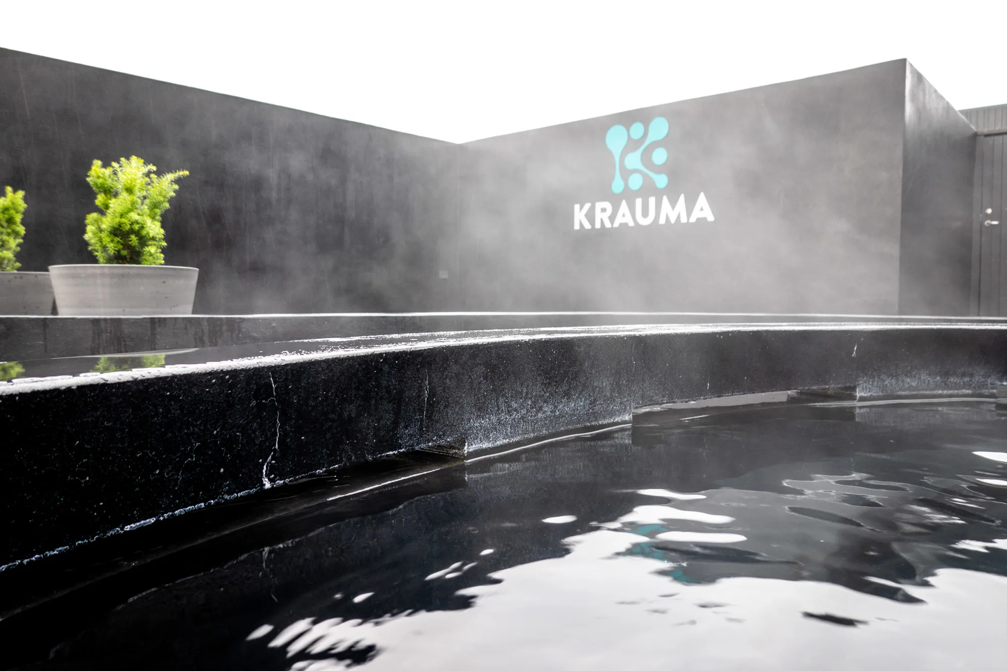 Black geothermal pool surrounded by black walls with a sign for "Krauma"