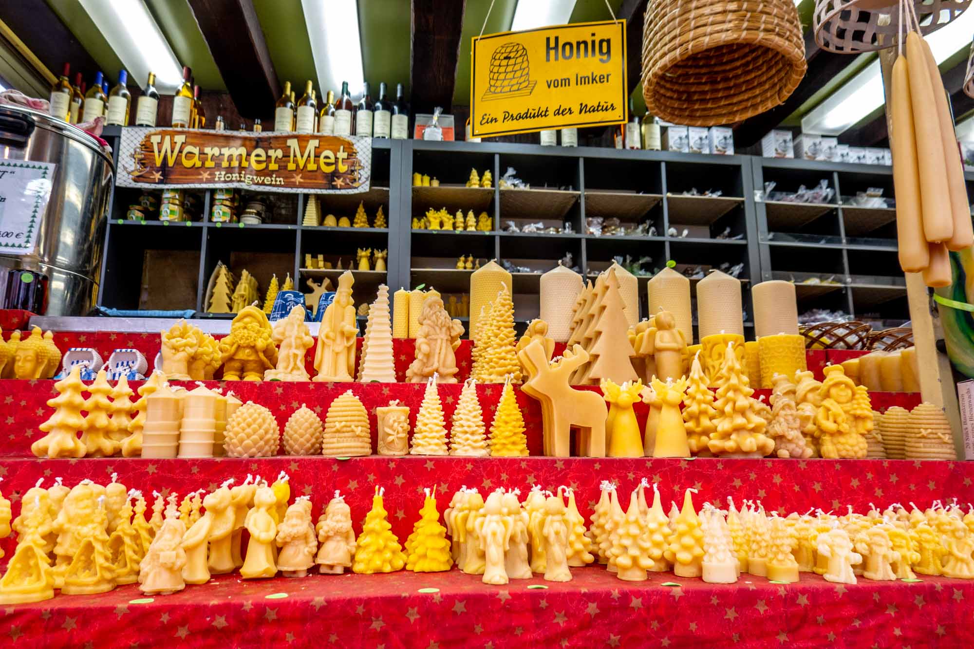 Rows of beeswax candles displayed for sale at a market