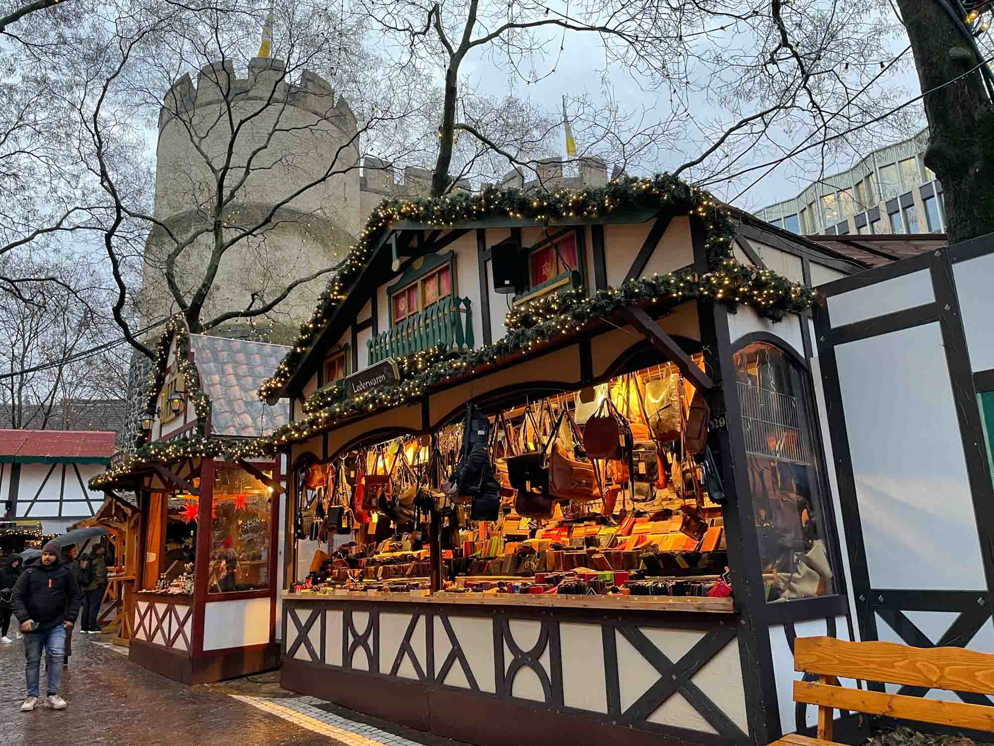 Half-timbered stall at a Christmas market with a large city gate in the background