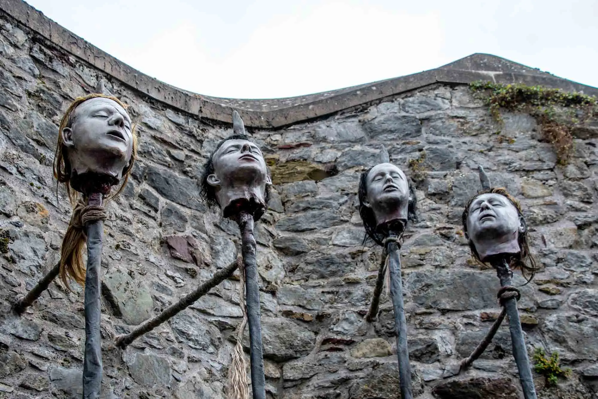 Four metal heads on spikes displayed in an ancient stone fort