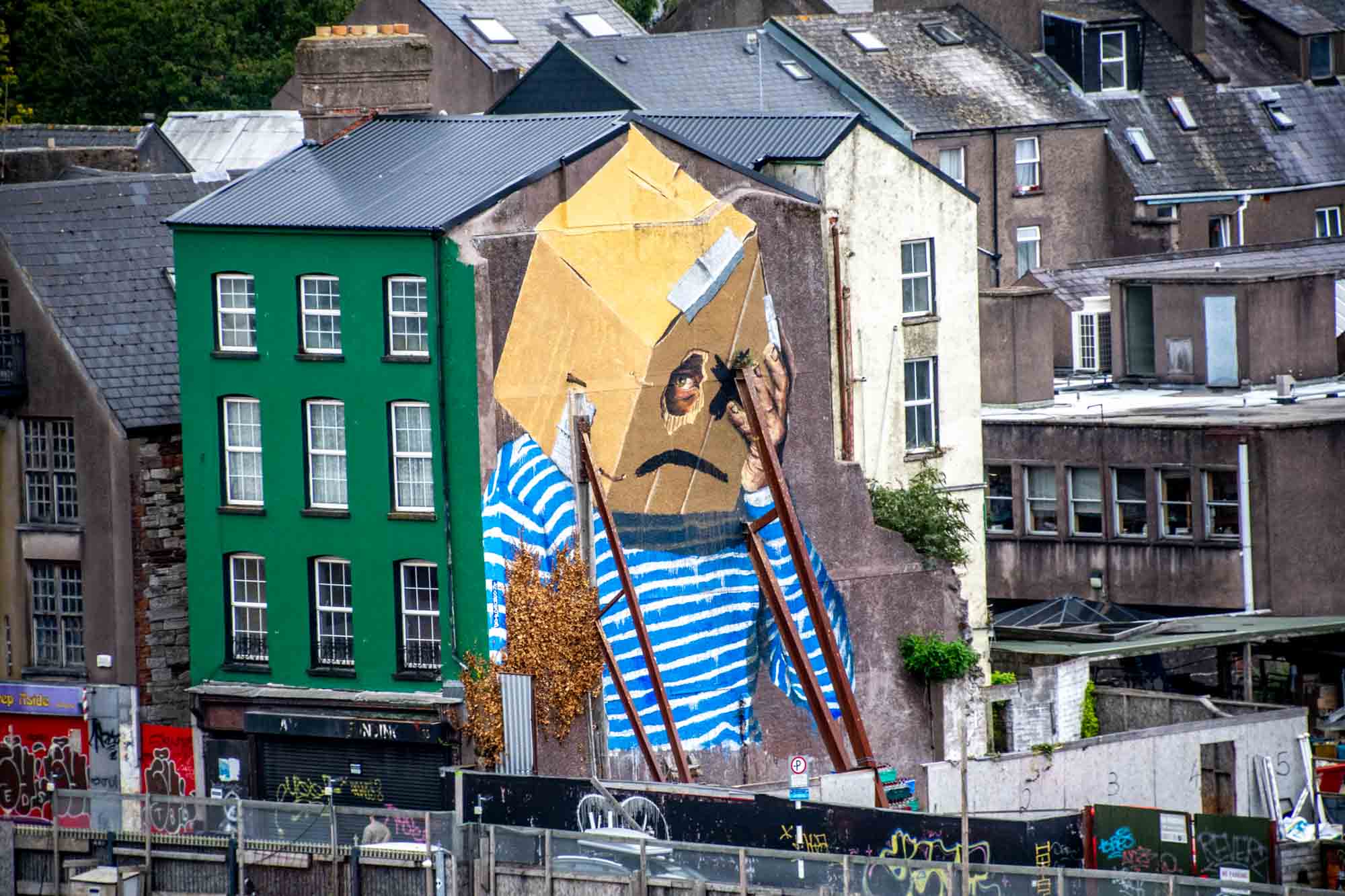 Street art mural of a person with a box on their head and one eye hole cut out