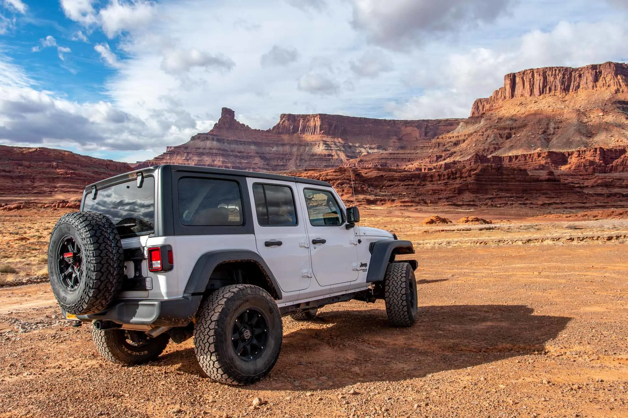 White Jeep in front of red rock cliffs