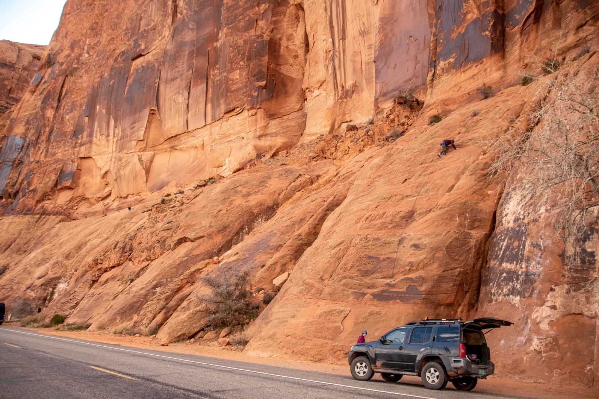 Rock climber ascending from car parked on Potash Road in Moab