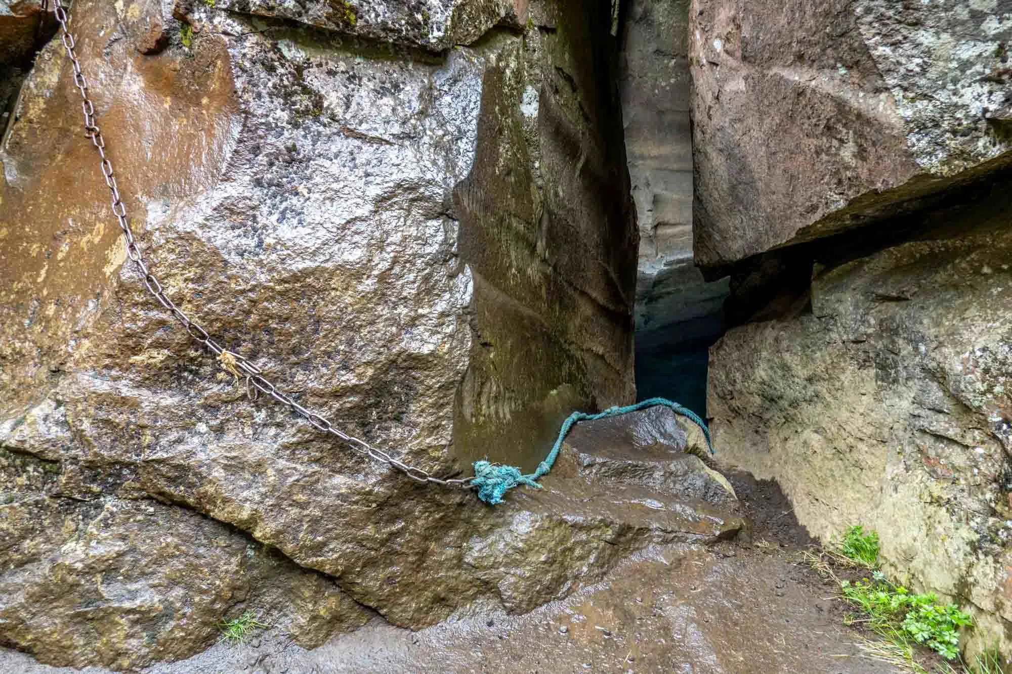 Steel chain and blue rope leading down into a cave