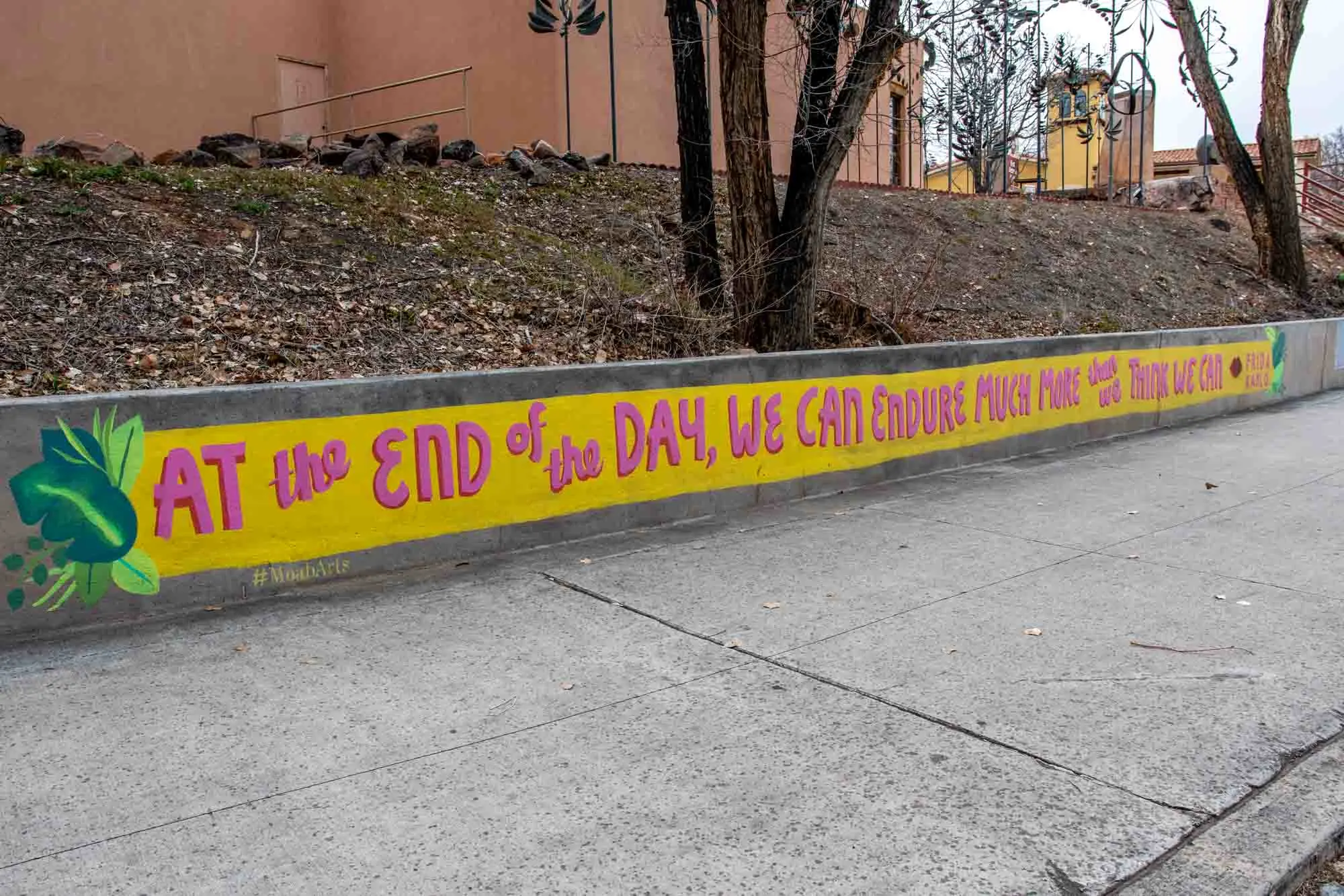 Mural on sidewalk with quote by Frida Kahlo that says, "At the end of the day, we can endure much more than we think we can."