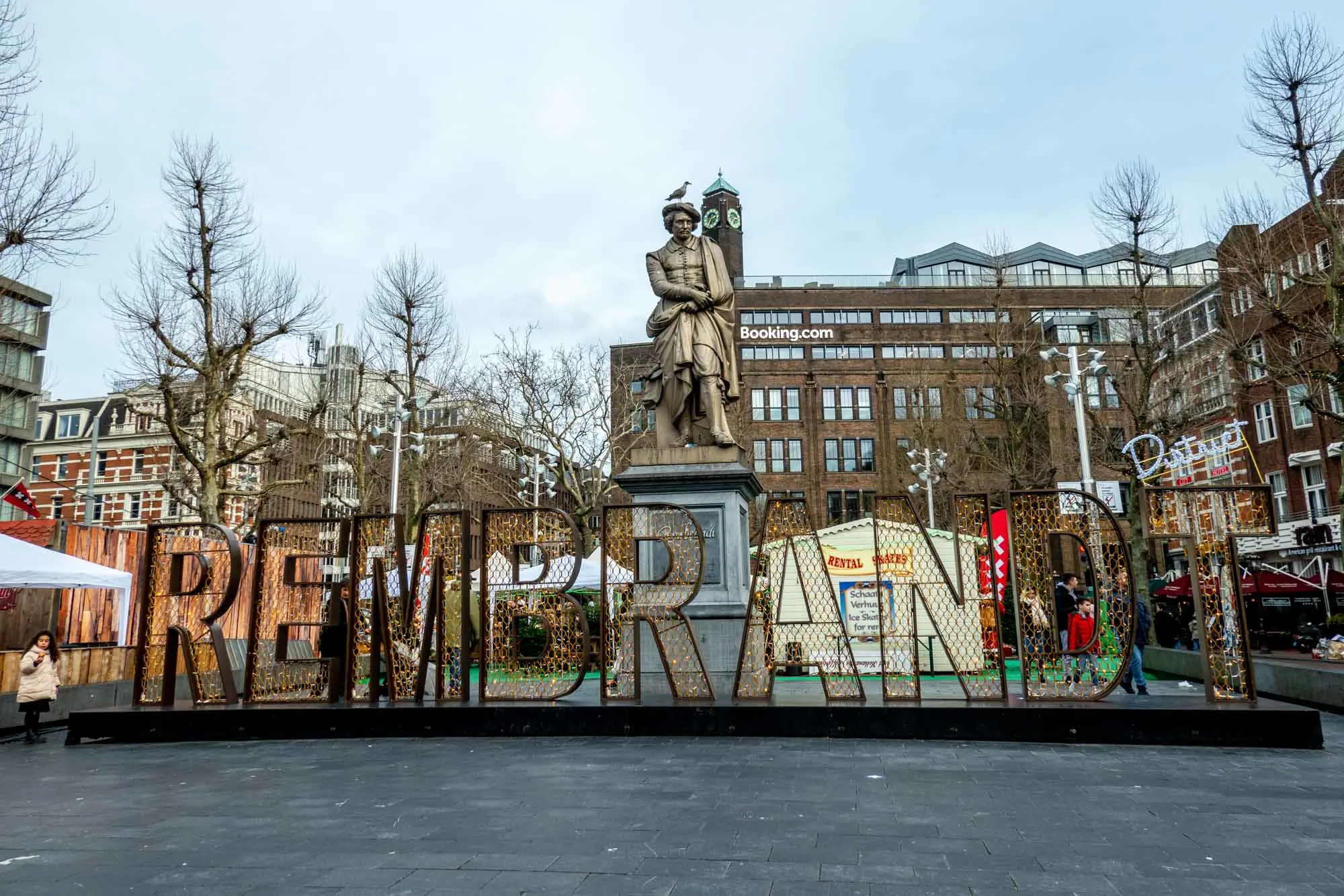 "Rembrandt" lit up with Christmas lights beside market stalls.