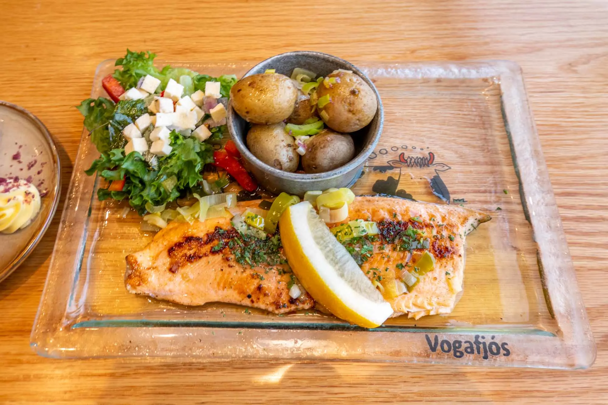 Arctic char with potatoes and salad on a plate that says "Vogafos"