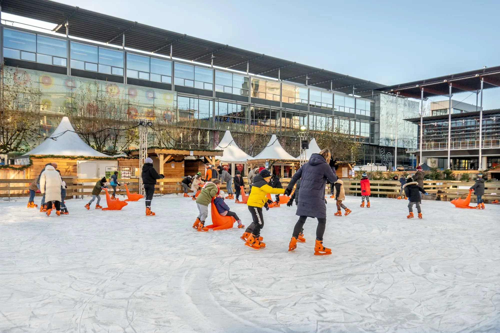 People skating on an ice-skating rink surrounded by market chalets.