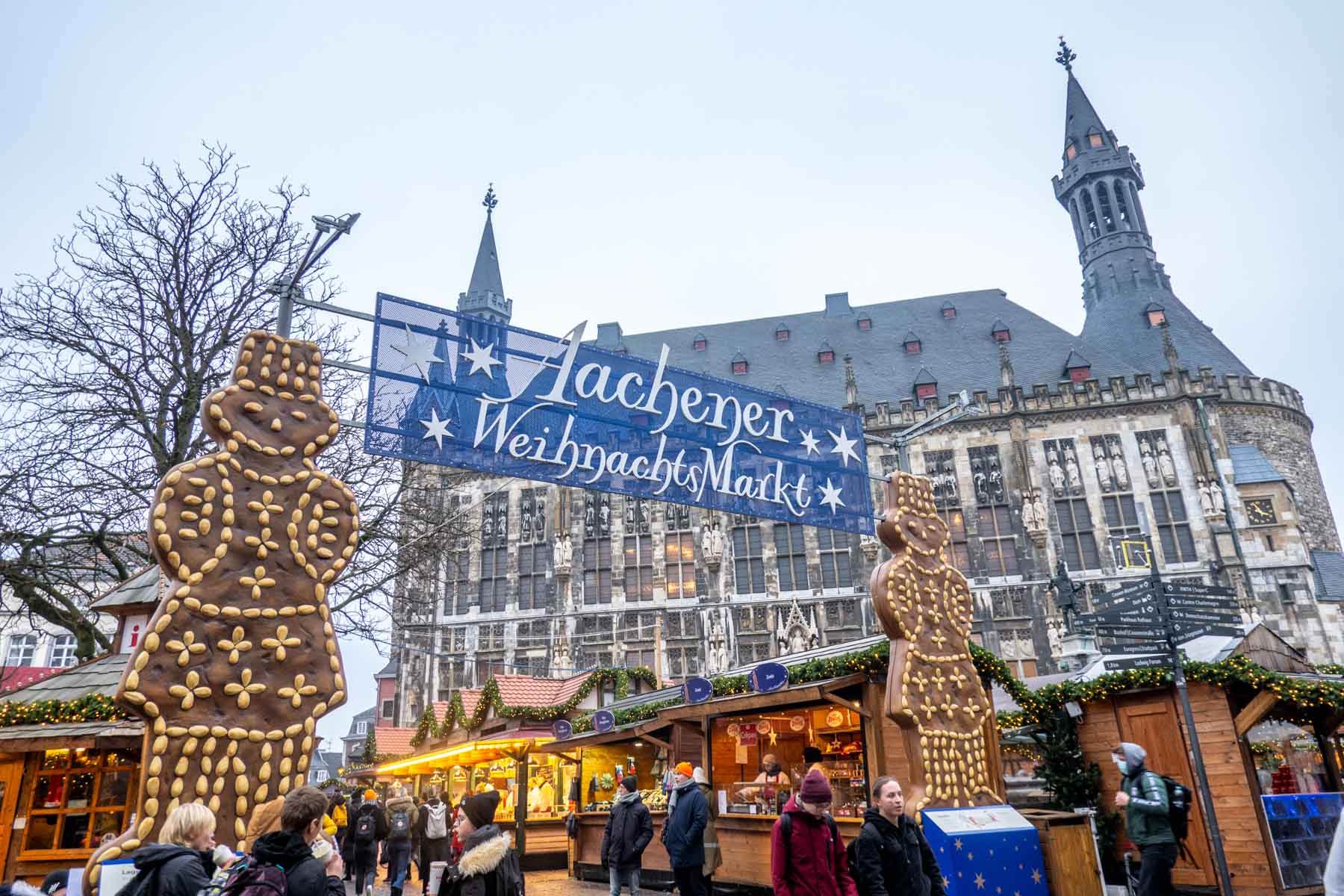 Gingerbread men beside a sign for the Aachen Christmas market and rows of vendor stalls