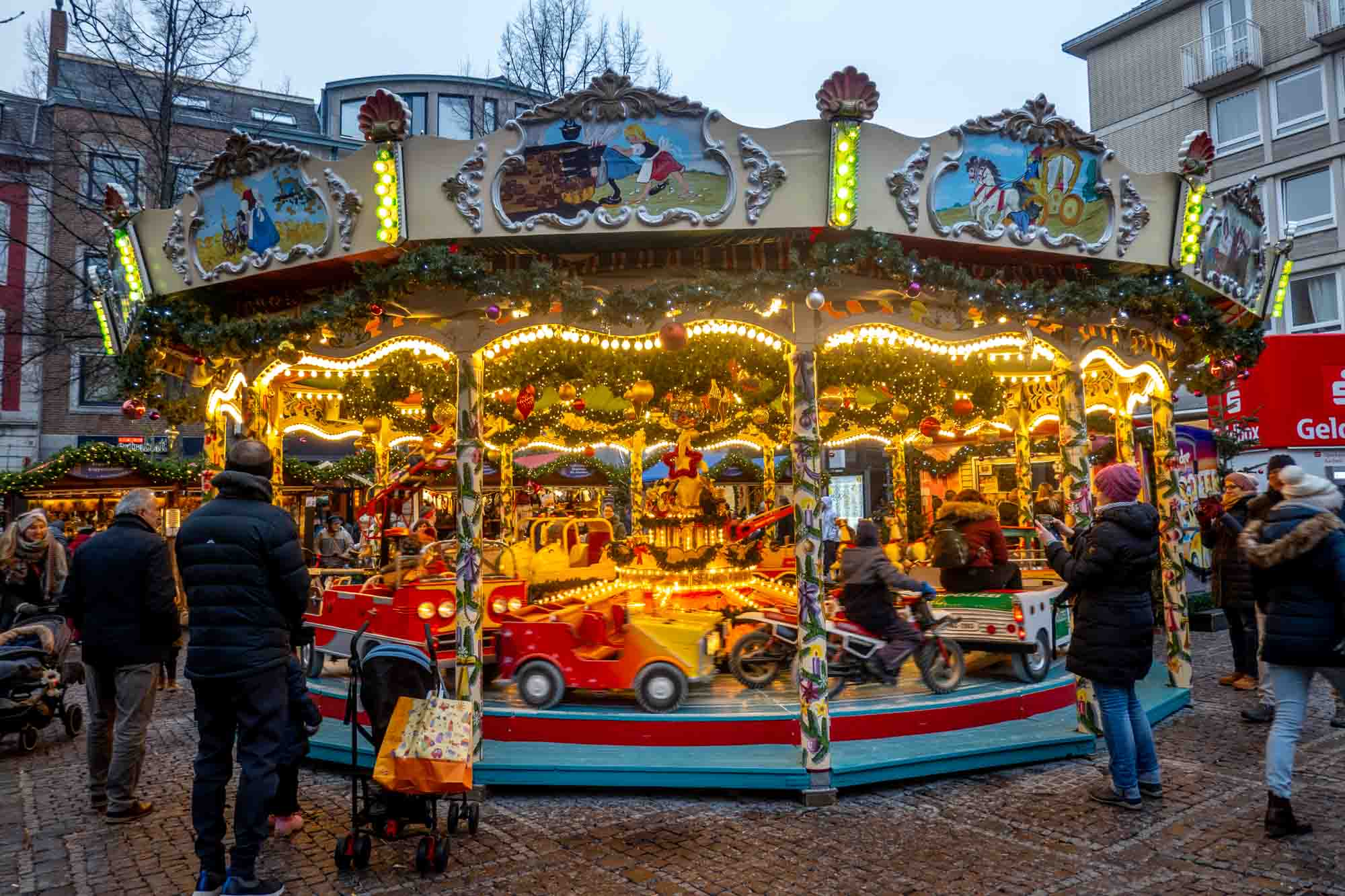 Children riding a carousel decorated with lights and holiday garland