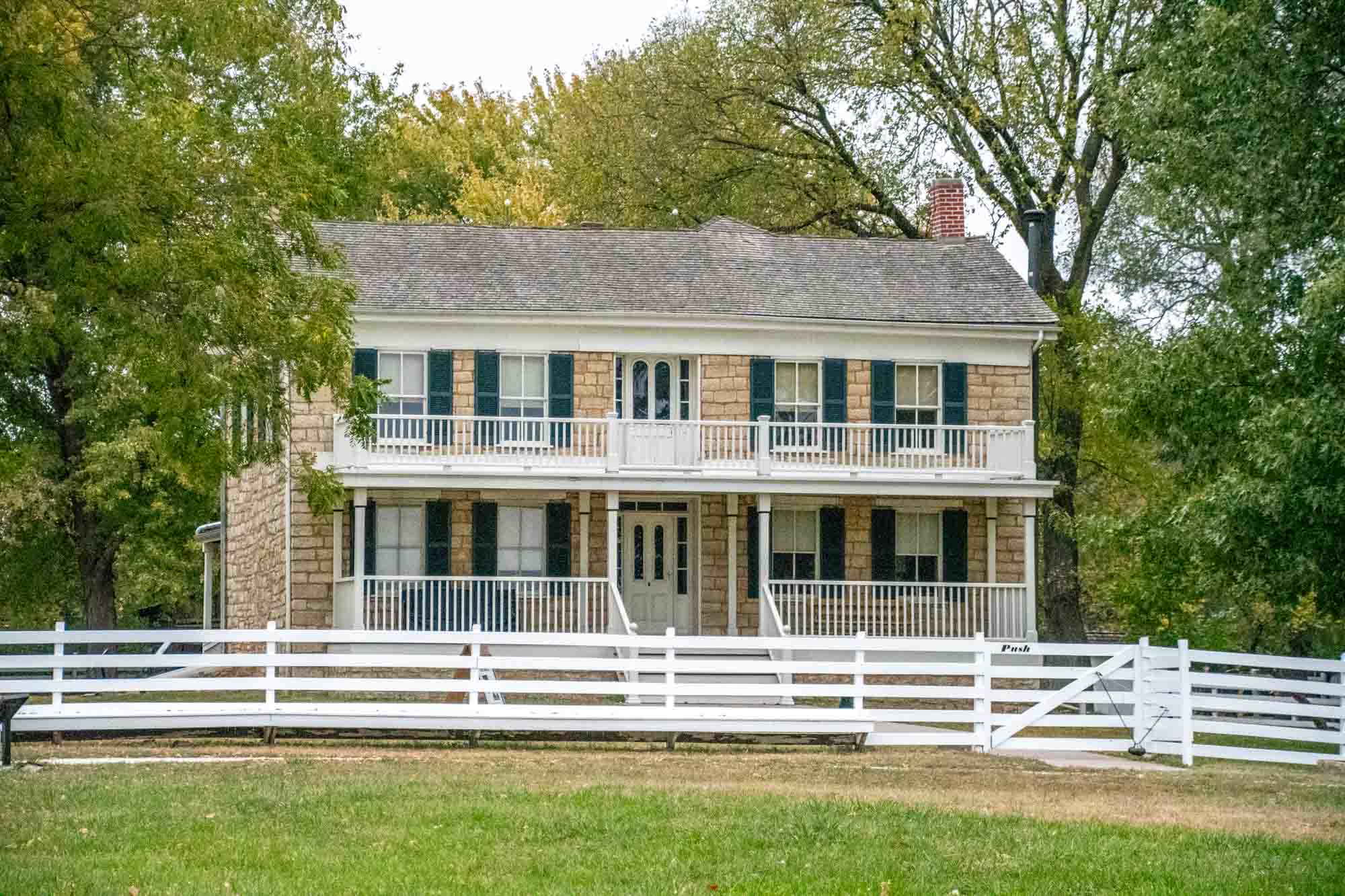 Two-story stone farmhouse  with white fence