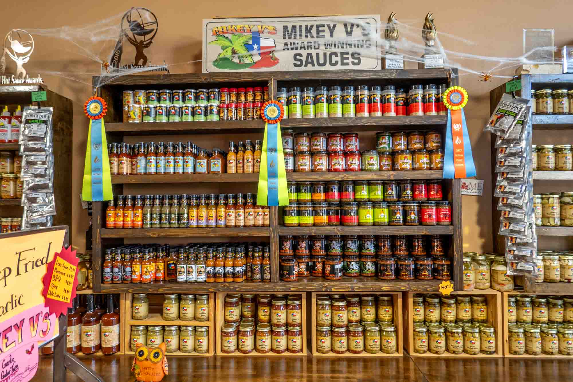 Shelves filled with bottles of hot sauce and a sign: "Mikey V's Award-Winning Sauces"