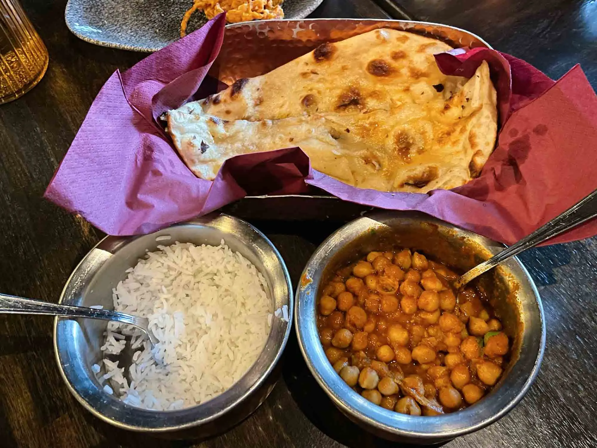 Tiffin bowls of chana masala, white rice, and naan bread