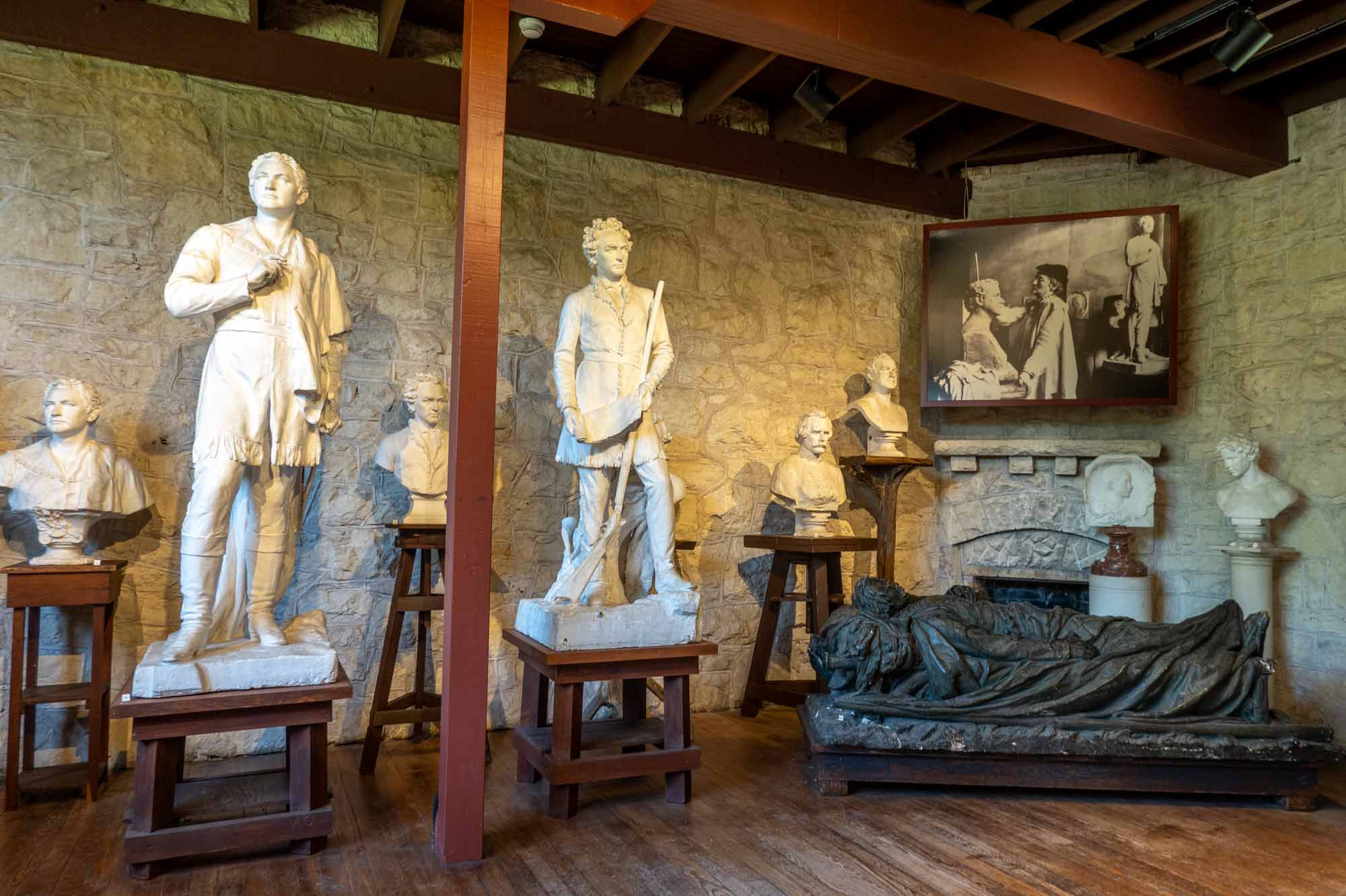 Sculptures displayed in a room with rustic stone walls