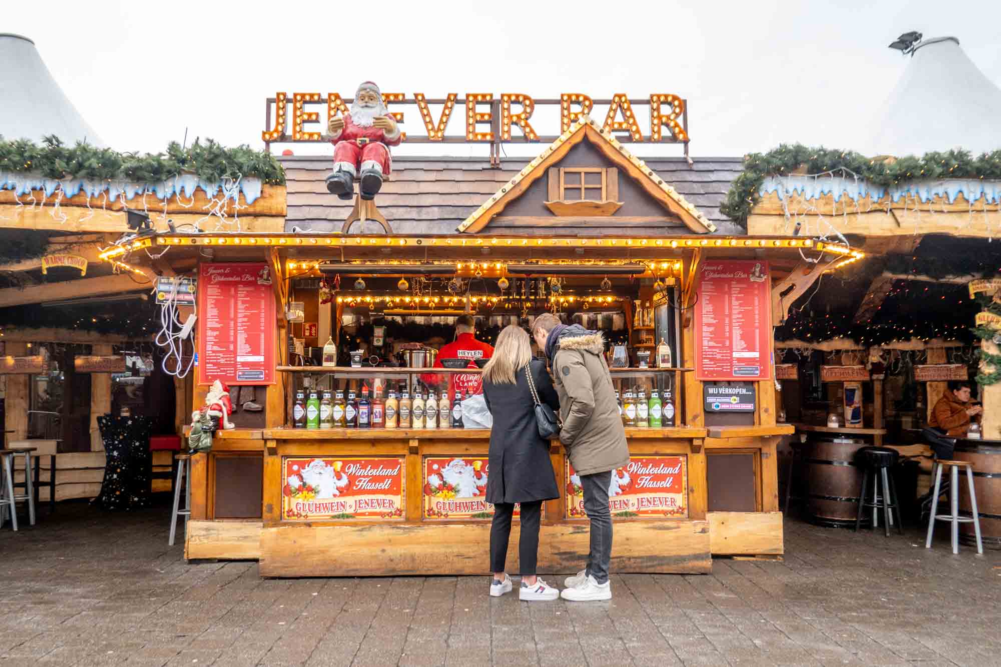People standing at a wooden chalet serving as a genever bar