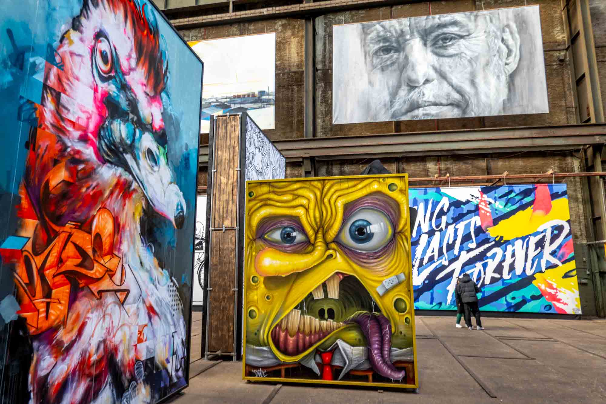 Multiple street art murals hanging in abandoned factory