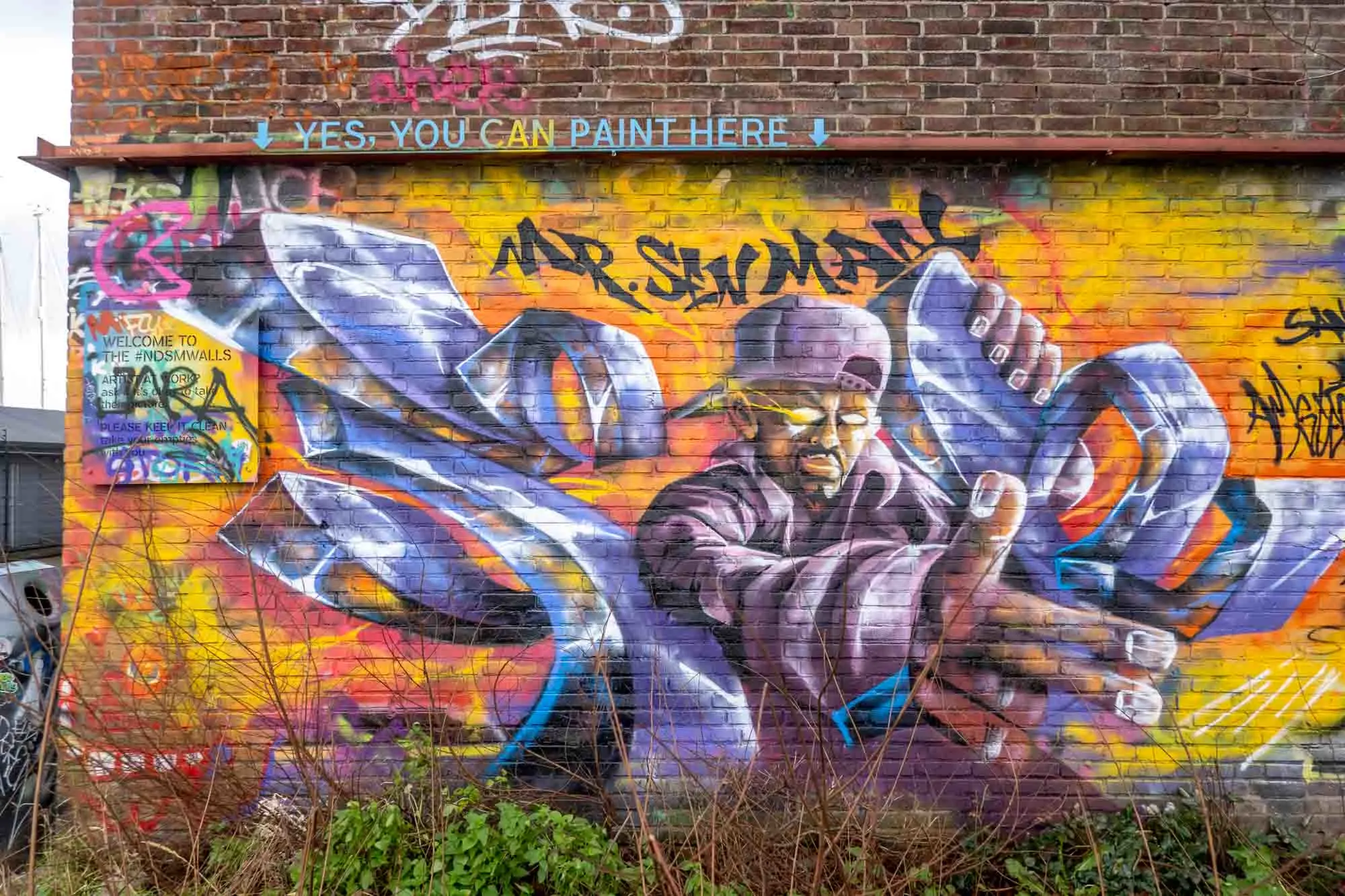Spray painted graffiti mural of man in purple clothes on the NDSM Walls
