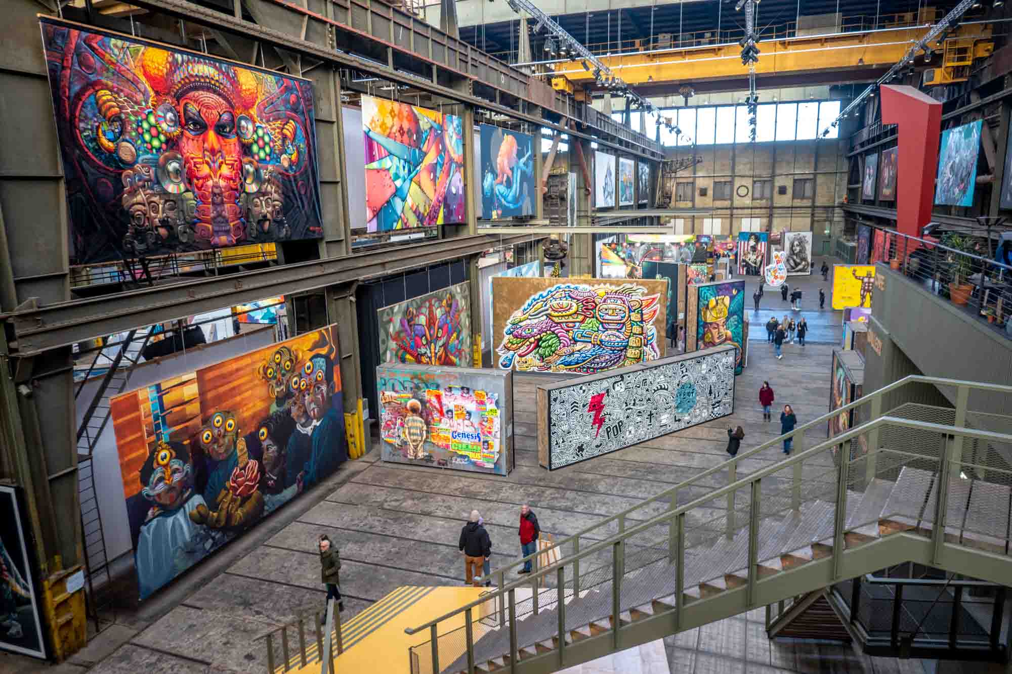 View of numerous large painted murals on canvases inside abandoned factory