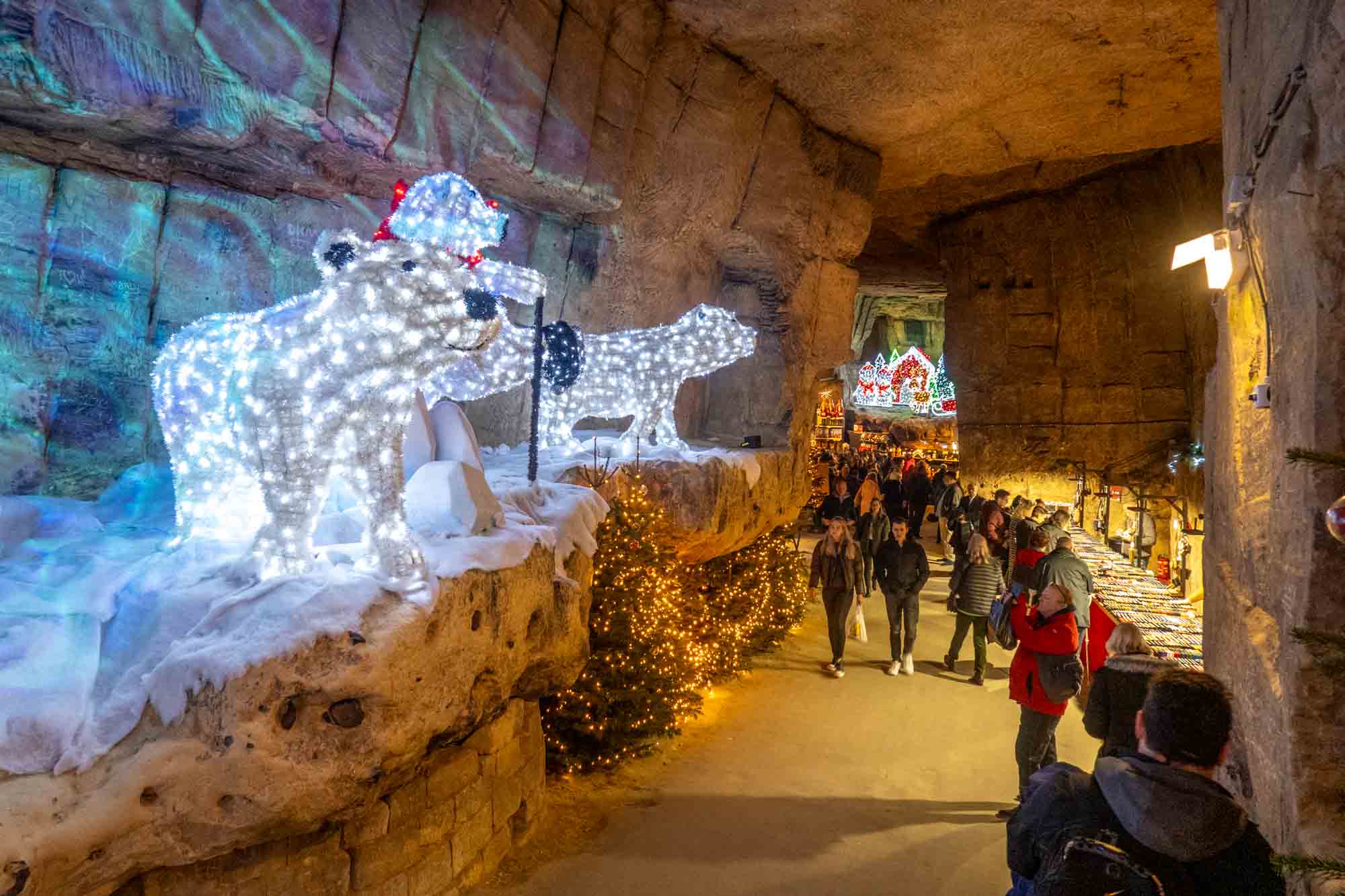 Christmas market shoppers in a cave decorated with light sculptures.